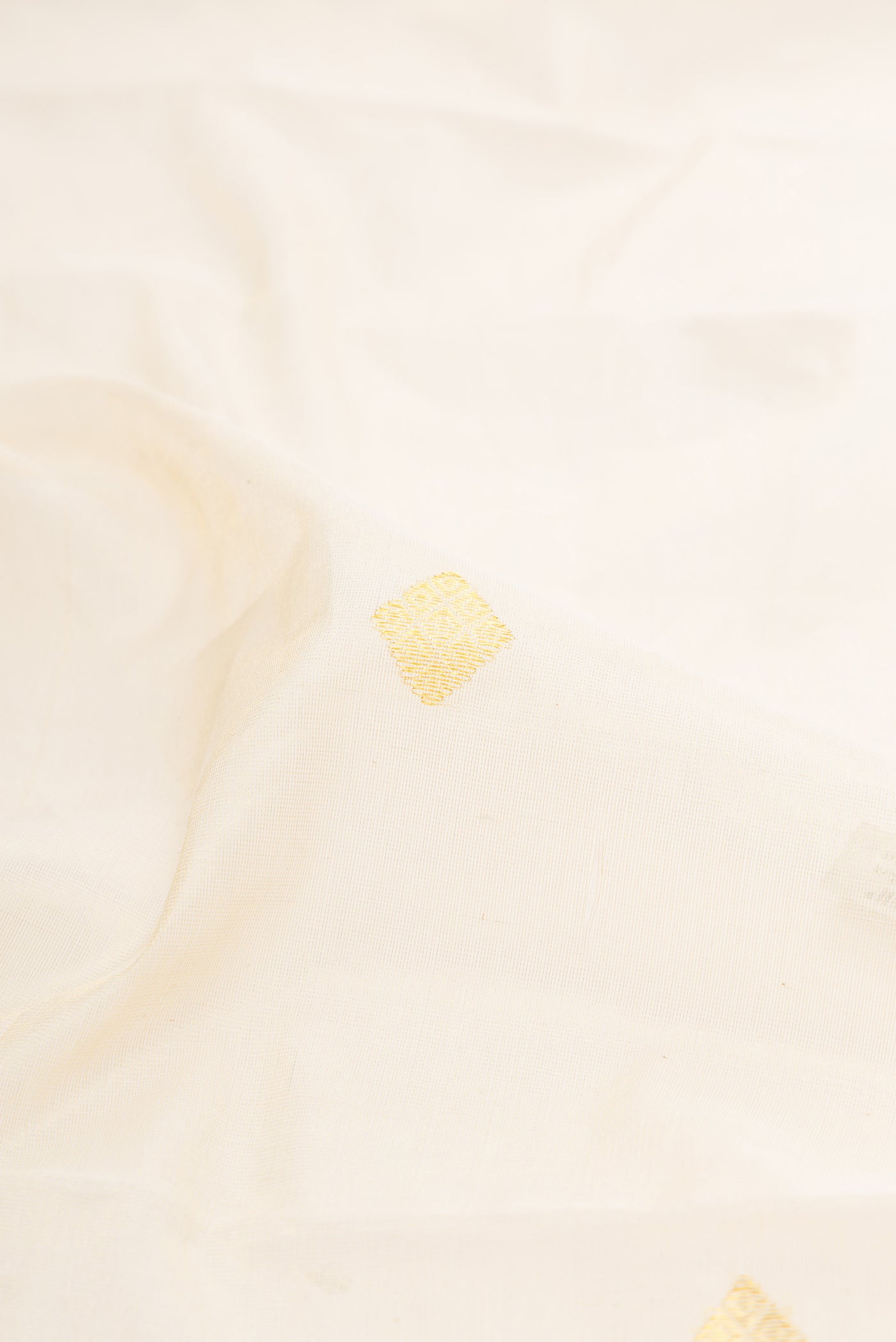 Close up of Off White Kerala Cotton Saree with Zari Butta on the body and Zari Border.  displaying folds