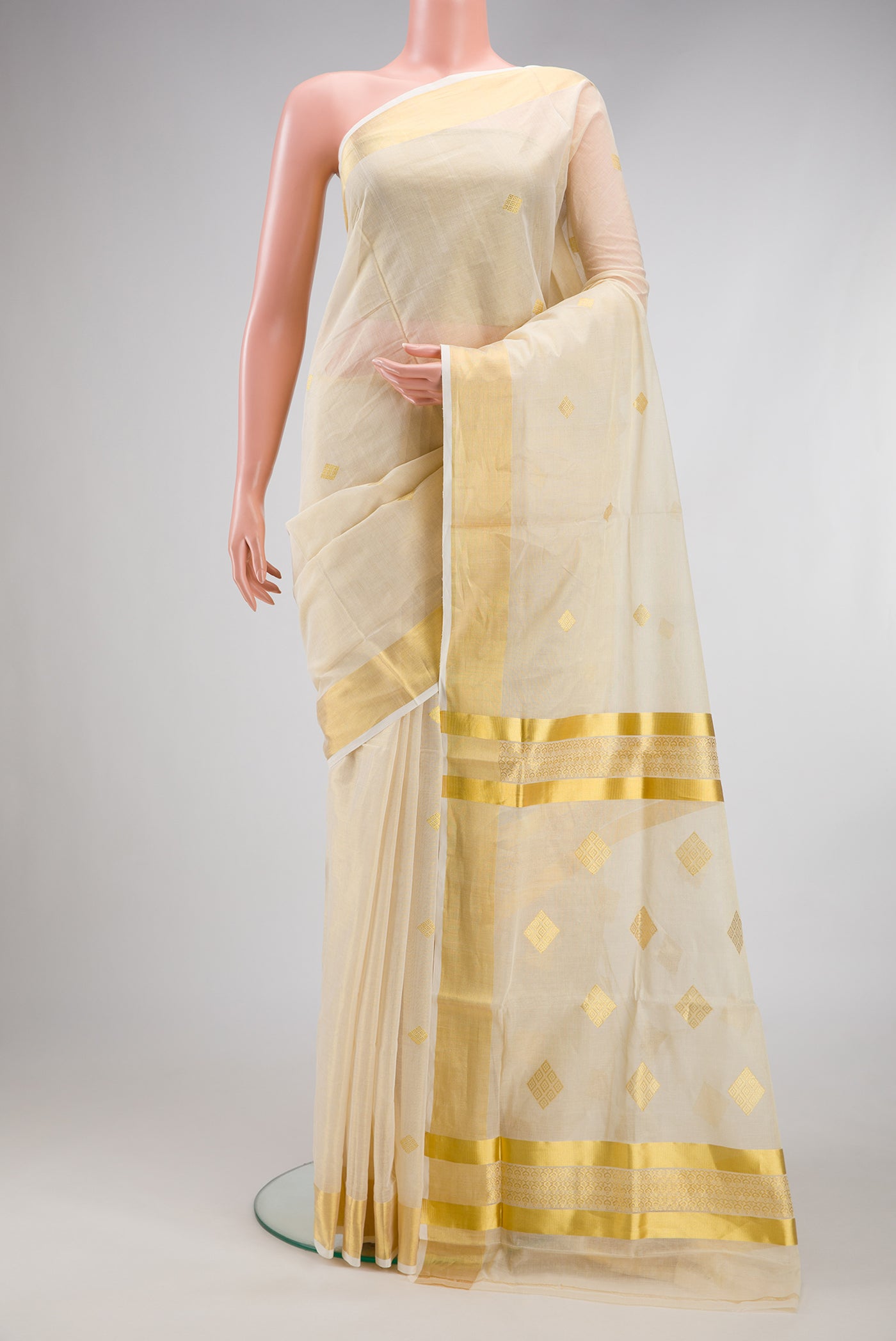Off White Kerala Cotton Saree with Zari Butta on the body and Zari Border.  displayed on a mannequin