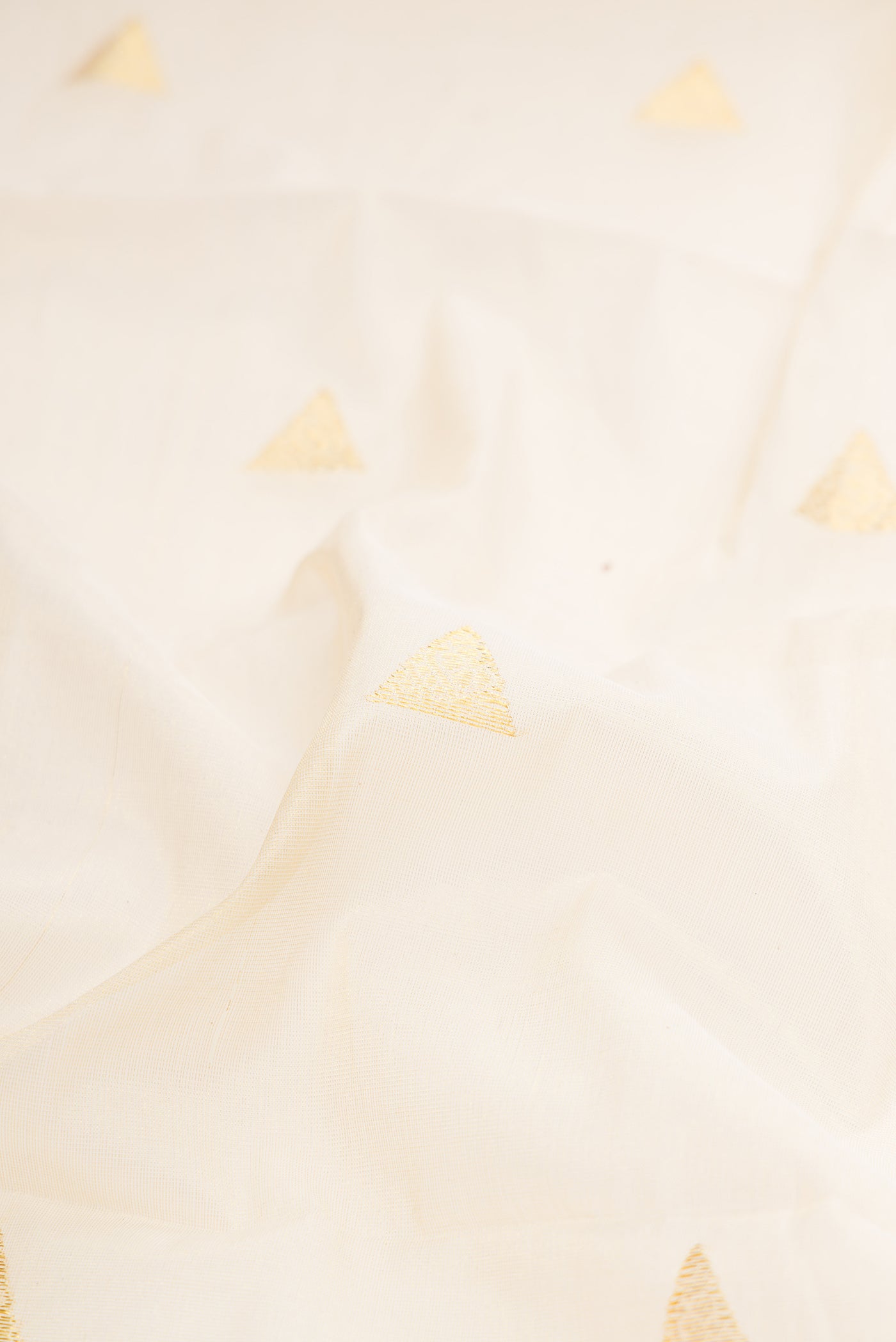 Close up of Off White Kerala Cotton Saree with Zari Butta on the body and Zari Border.  displaying folds