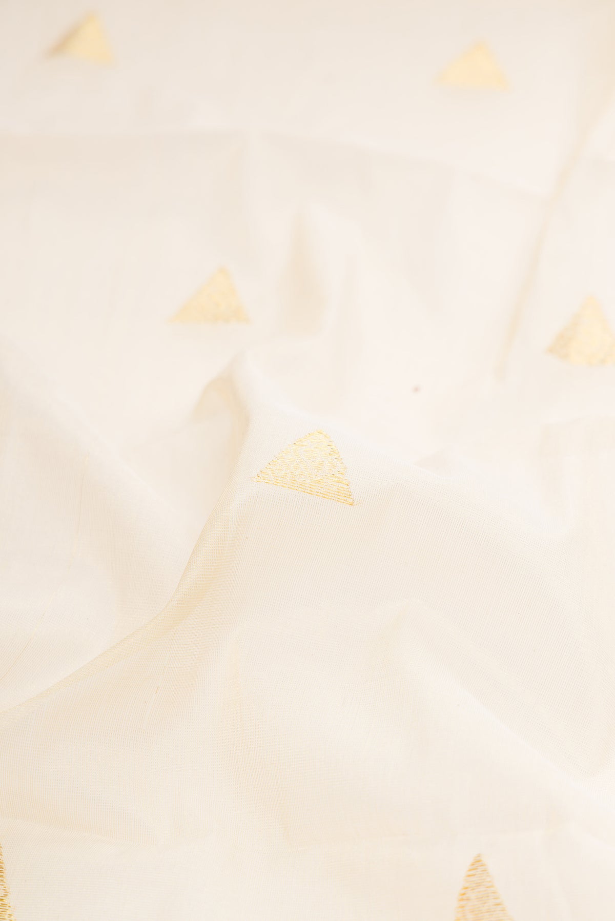 Close up of Off White Kerala Cotton Saree with Zari Butta on the body and Zari Border.  displaying folds