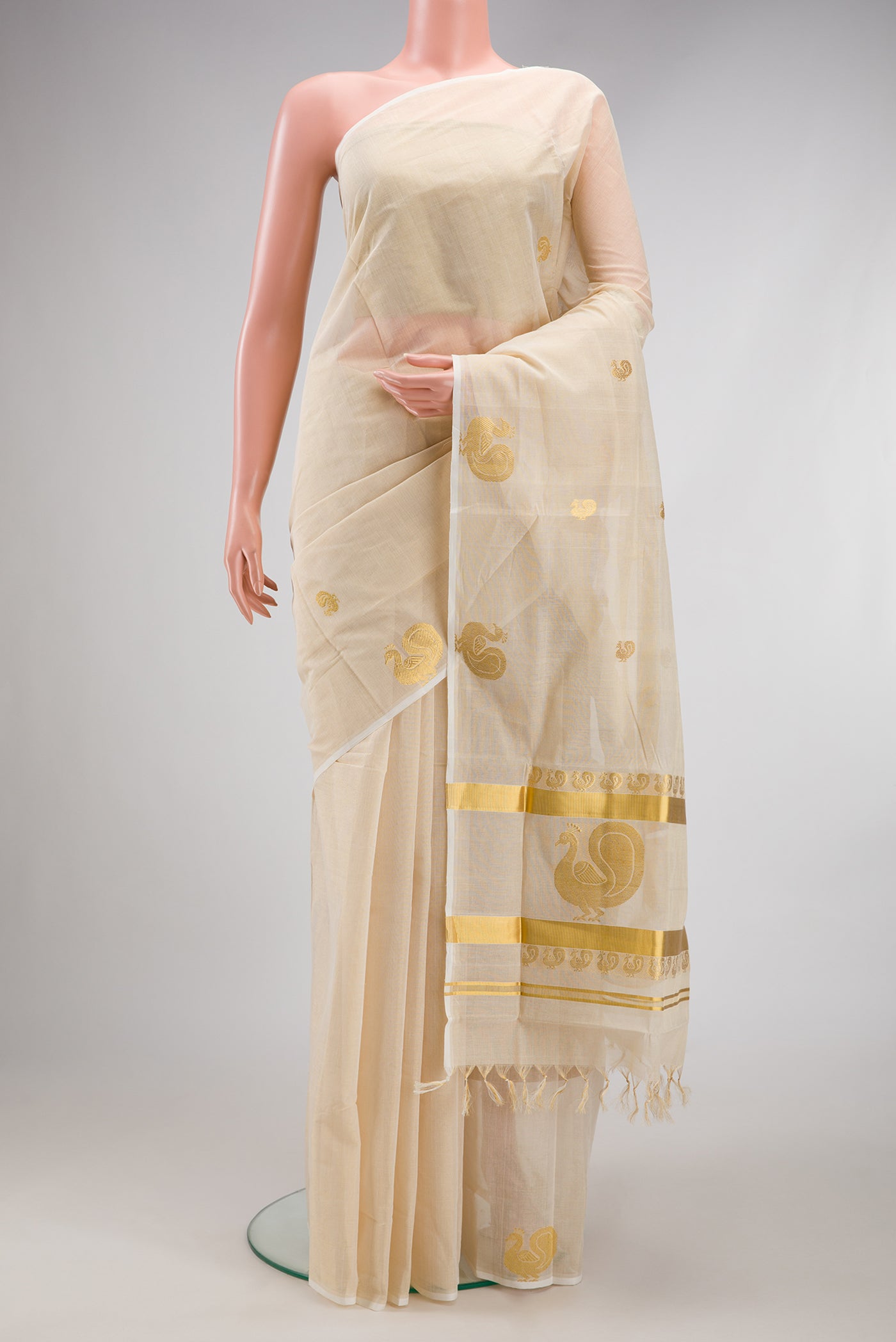 Off White Kerala Cotton Saree with Zari Butta on the body and Fancy Border.  displayed on a mannequin