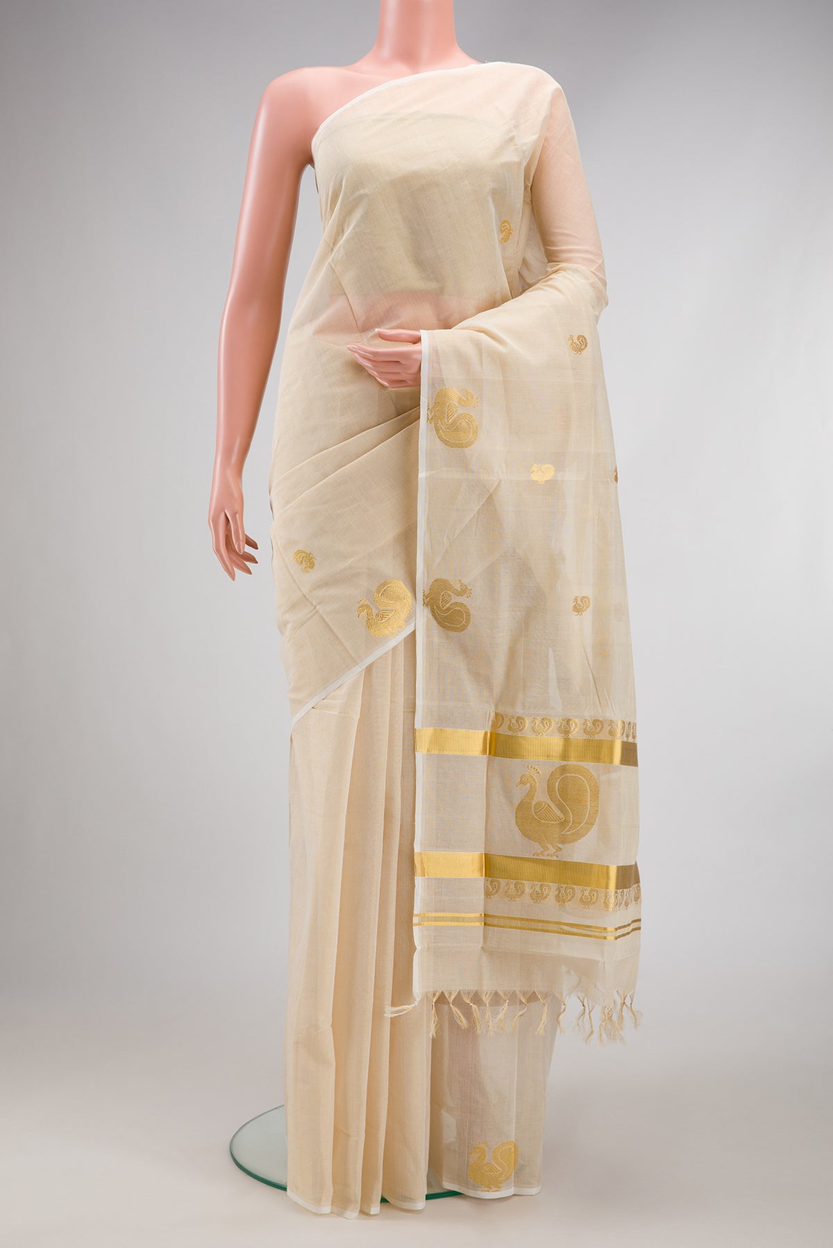 Off White Kerala Cotton Saree with Zari Butta on the body and Fancy Border.  displayed on a mannequin