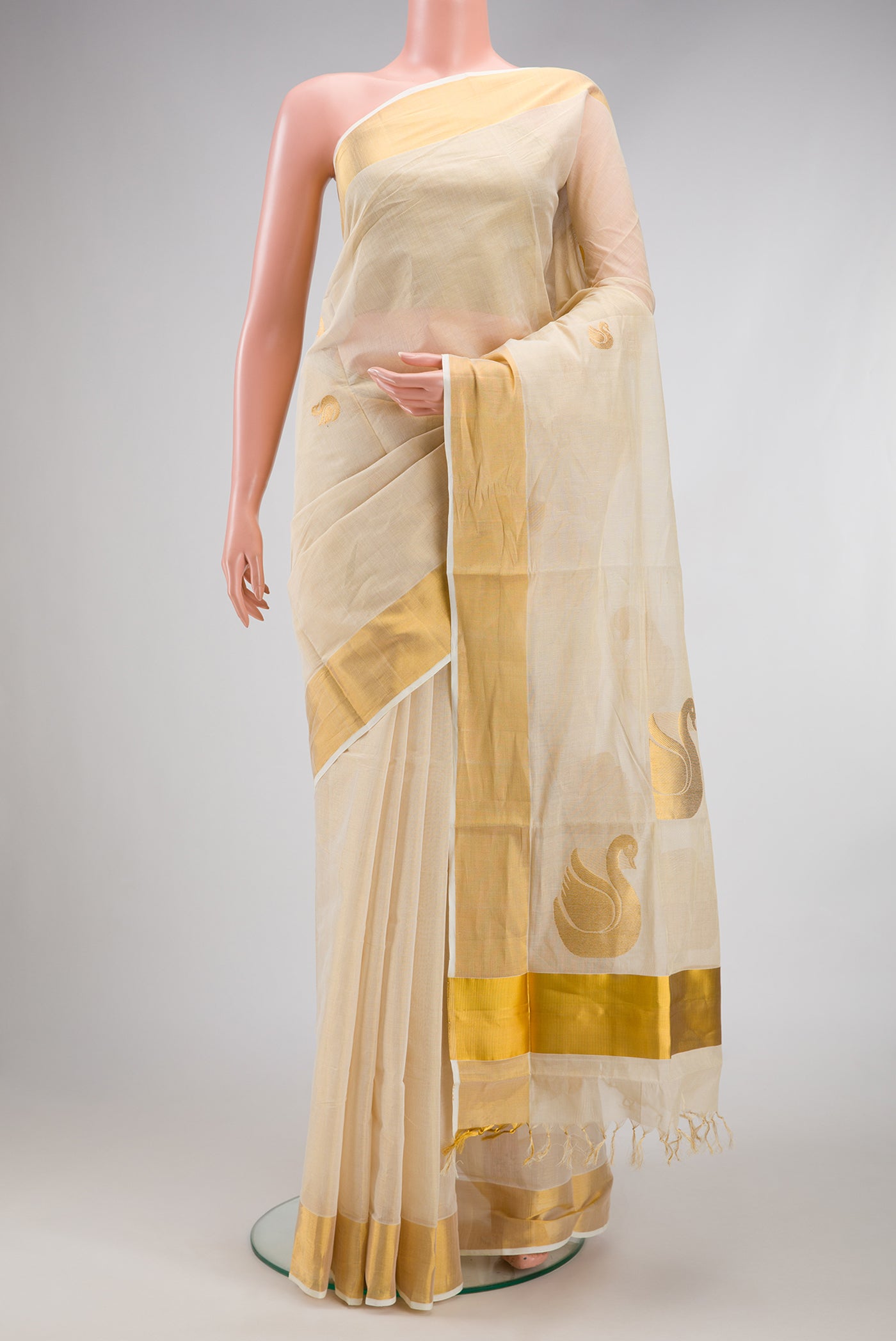 Off White Kerala Cotton Saree with Zari Butta on the body and Zari Border.  displayed on a mannequin