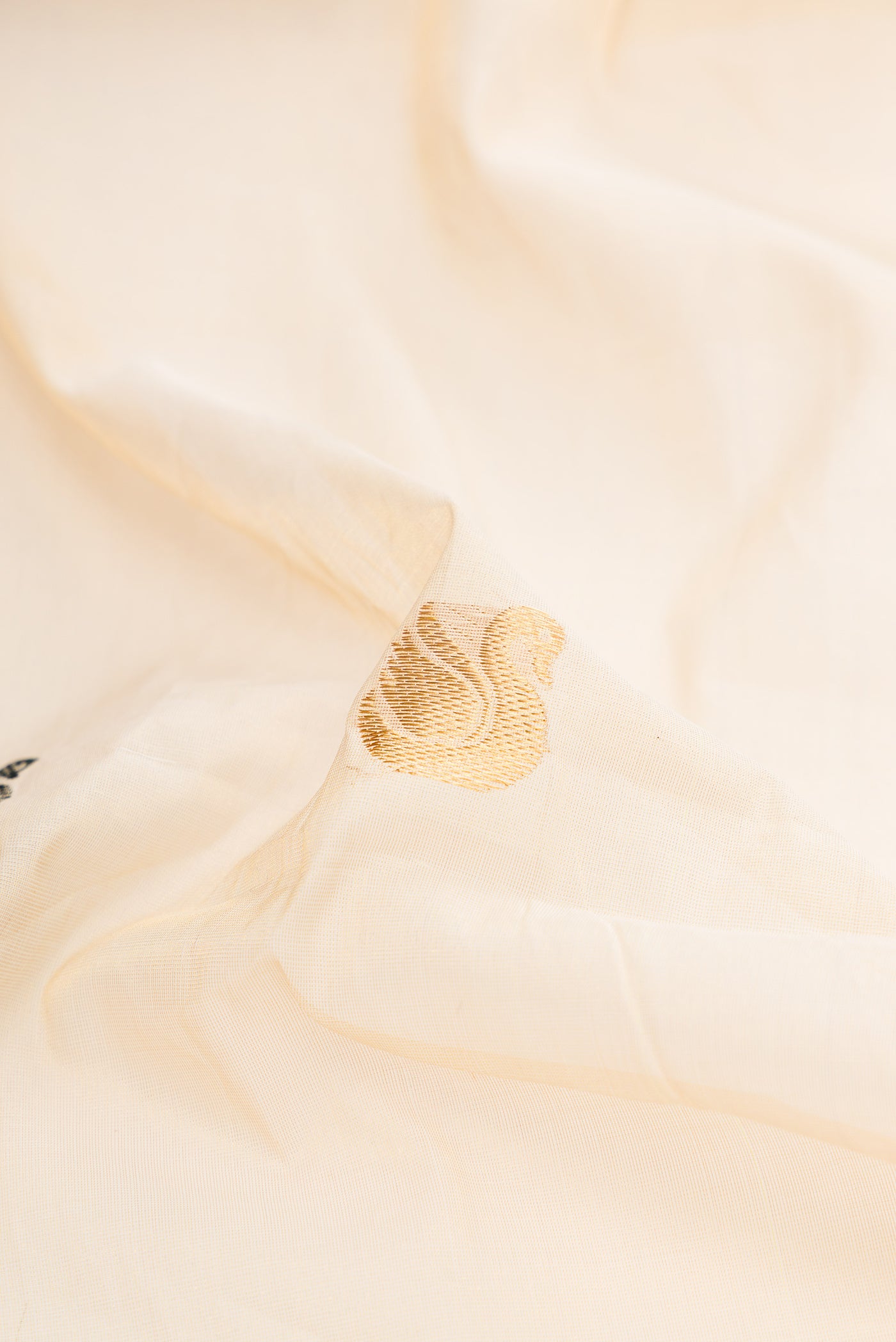 Close up of Off White Kerala Cotton Saree with Zari And Thread Butta on the body and Zari Border.  displaying folds