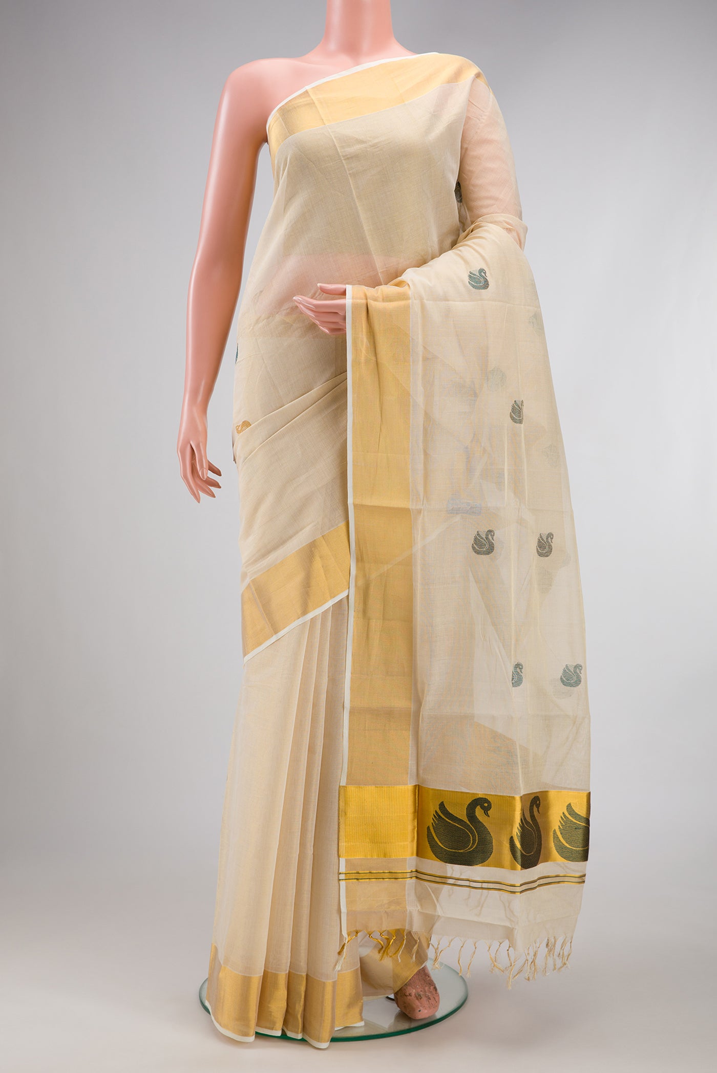 Off White Kerala Cotton Saree with Zari And Thread Butta on the body and Zari Border.  displayed on a mannequin