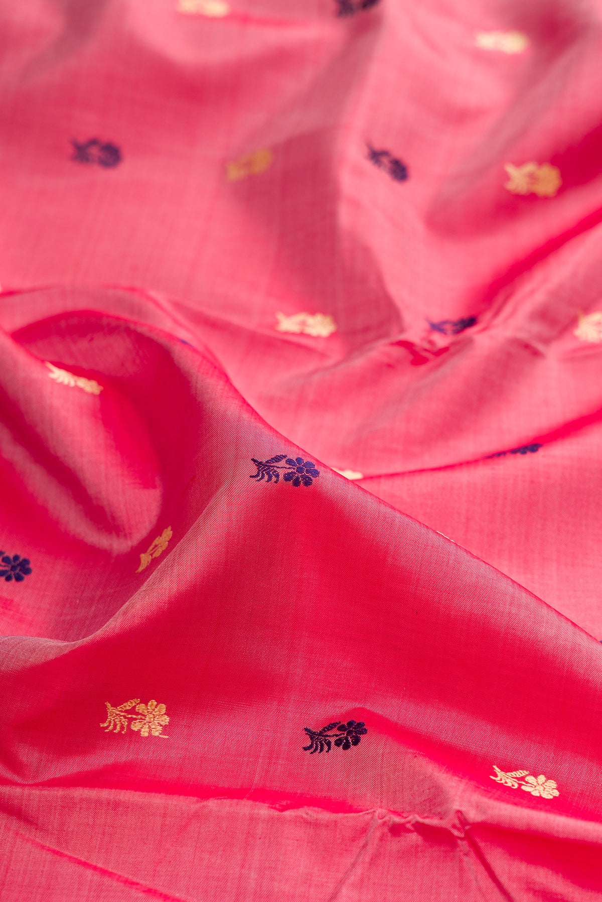 Close up of Coral Baluchari Silk Saree with Thread Butta on the body and Thread Border.  displaying folds