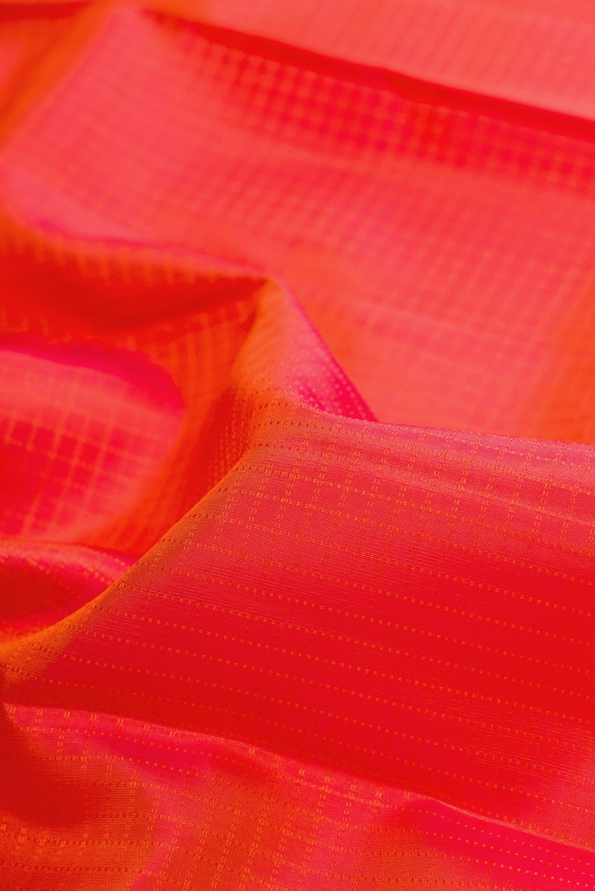 Close up of Pure Silk Orange Dual Tone Kanchipuram Saree with Checked design on the body and Zari Border.  displaying folds