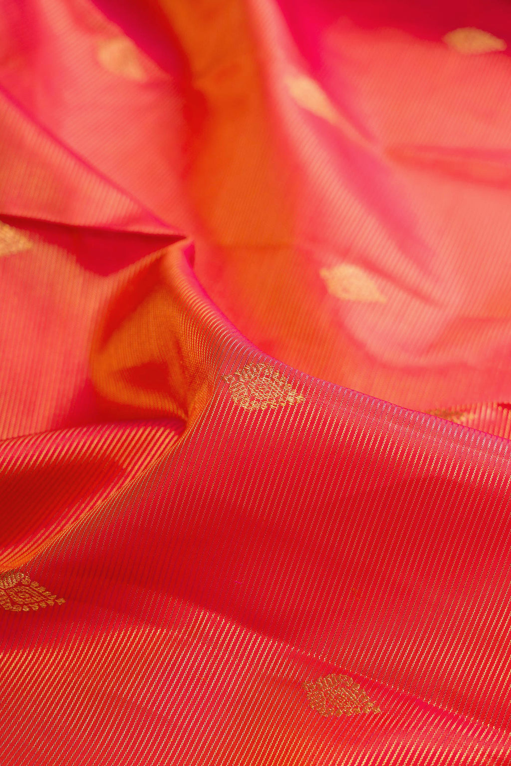 Close up of Pure Silk Coral Dual Tone Kanchipuram Saree with Zari Butta on the body and Zari Border.  displaying folds