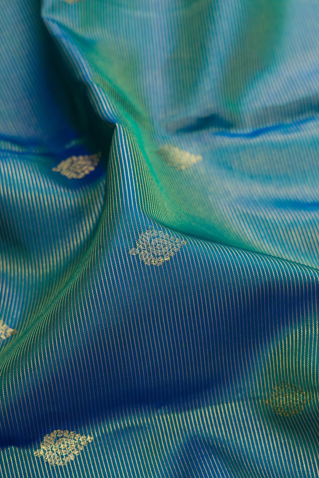 Close up of Pure Silk Peacock Blue Dual Tone Kanchipuram Saree with Stripes on the body and Zari Border.  displaying folds