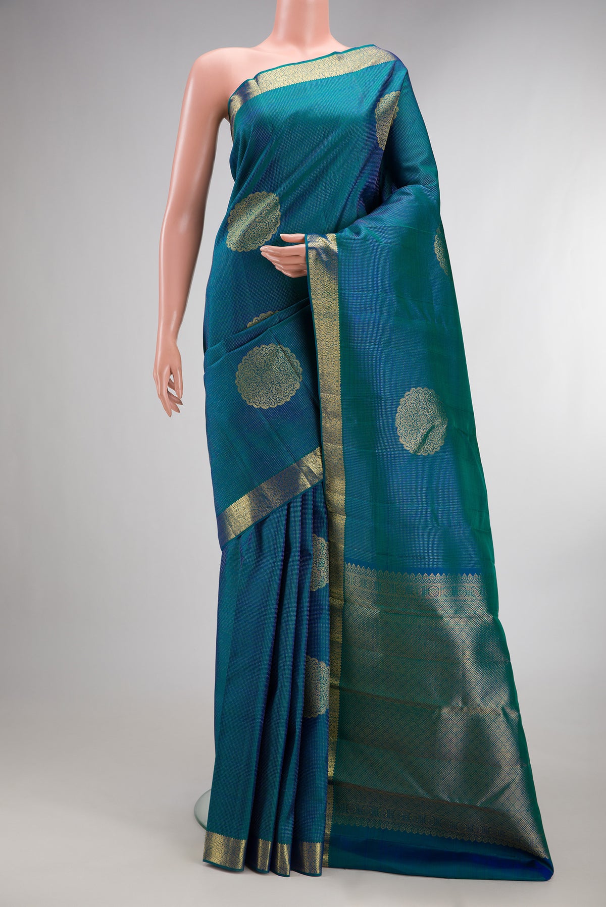 Pure Silk Peacock Blue Dual Tone Kanchipuram Saree with Zari Butta on the body and Zari Border.  displayed on a mannequin