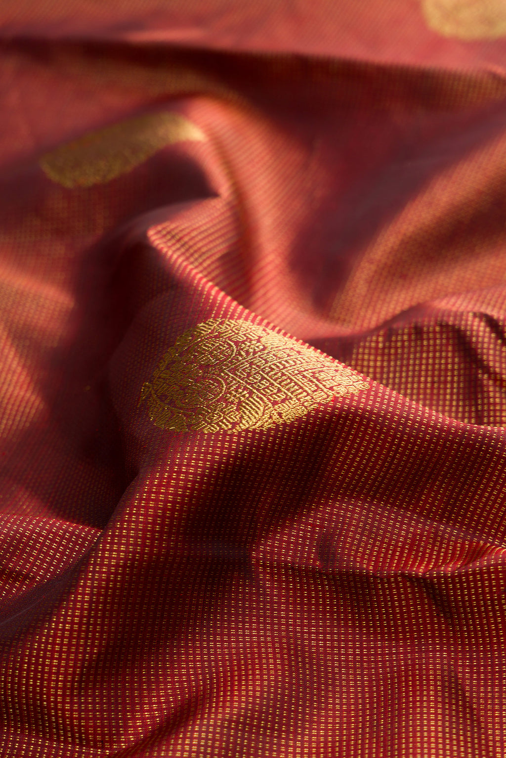 Close up of Pure Silk Maroon Kanchipuram Saree with Zari Butta on the body and Zari Border.  displaying folds