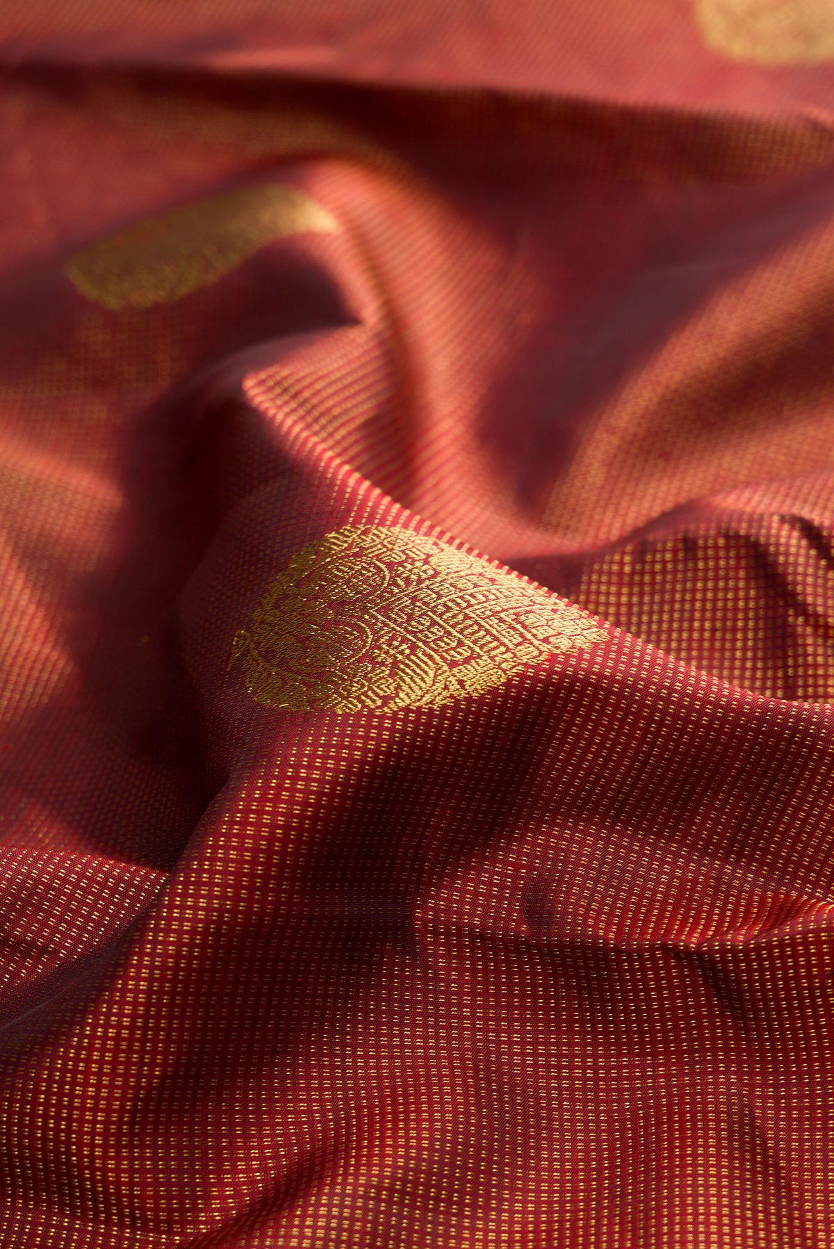 Close up of Pure Silk Maroon Kanchipuram Saree with Zari Butta on the body and Zari Border.  displaying folds