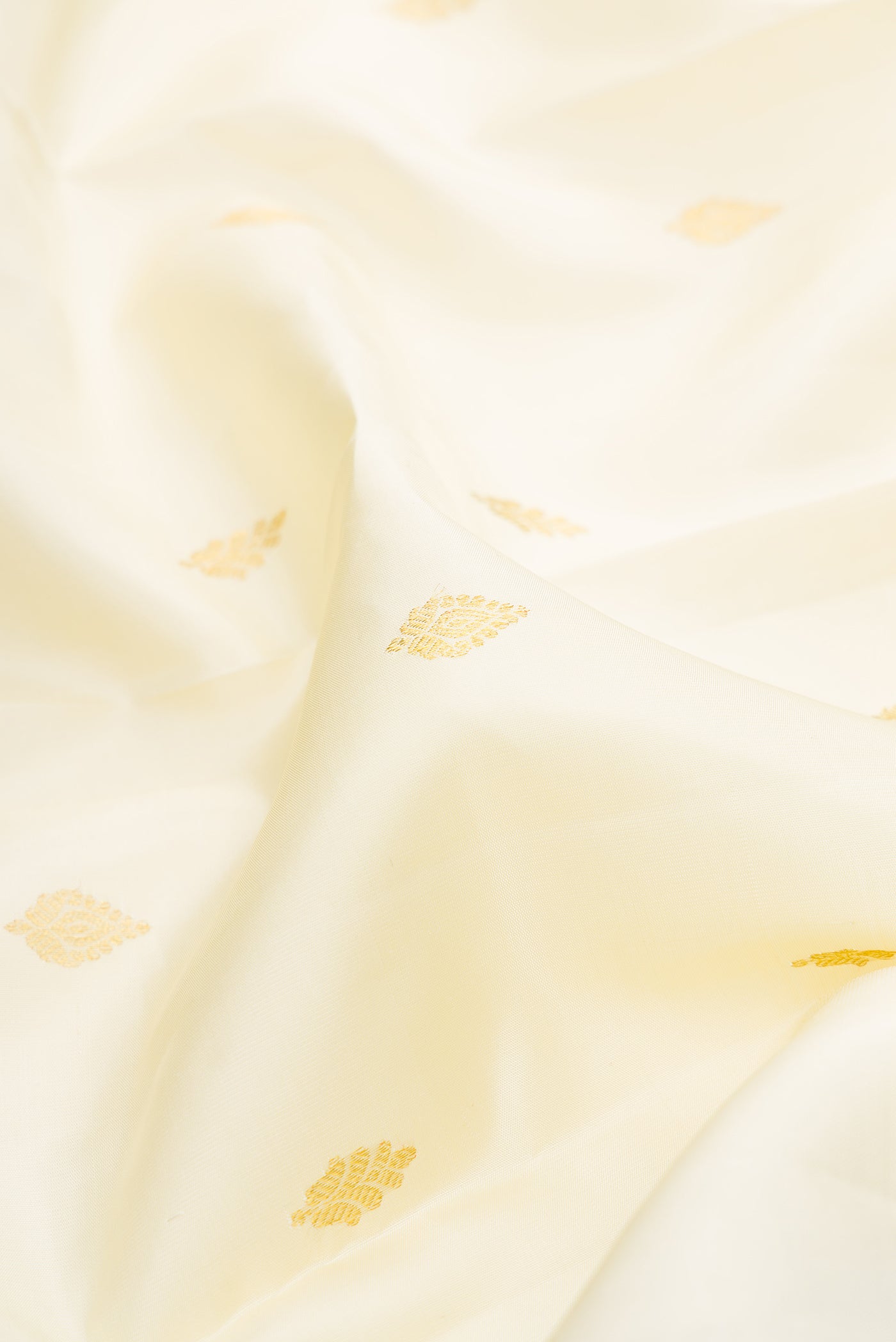 Close up of Off White Kanjivaram Silk Saree with Zari Butta on the body and Zari Border.  displaying folds