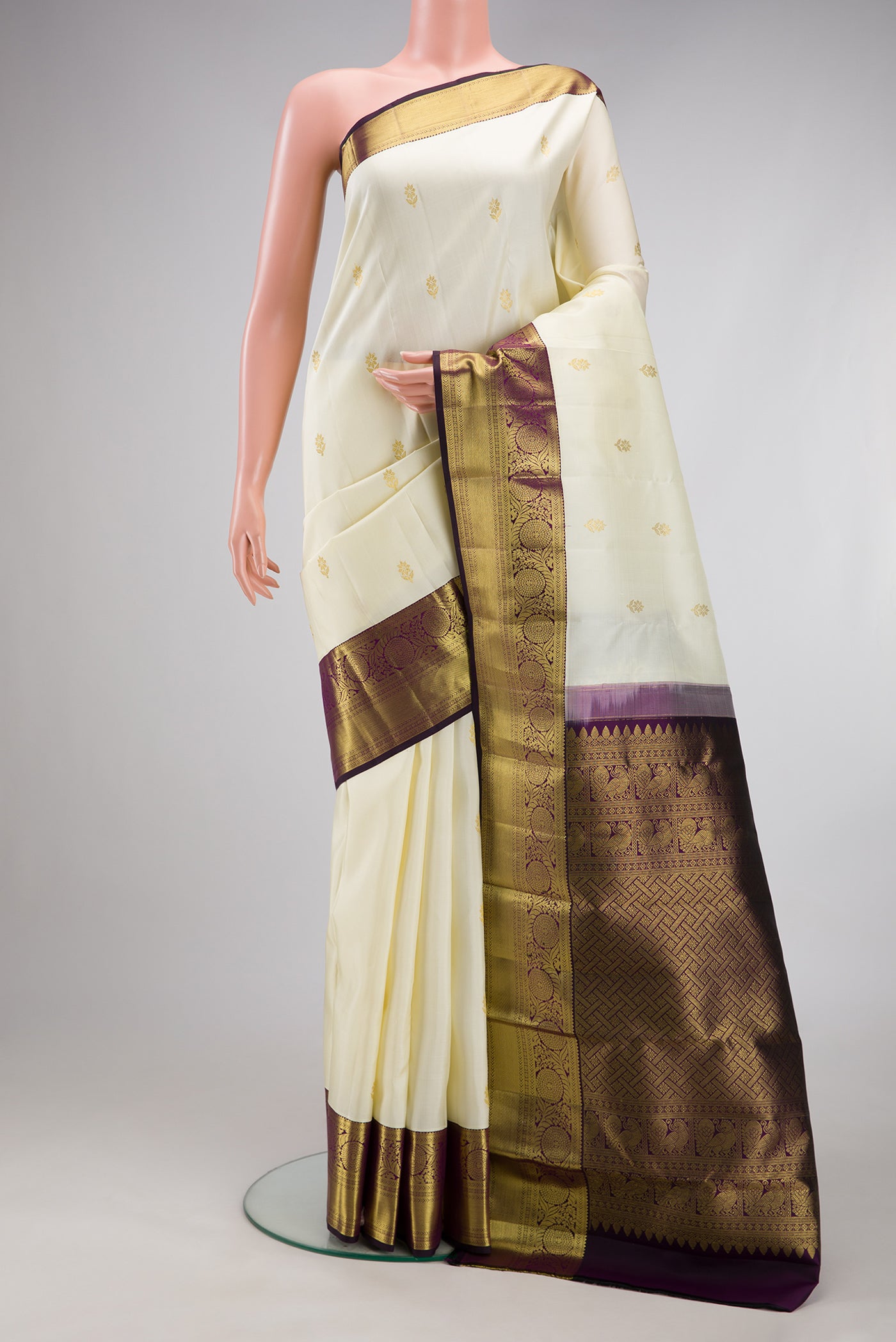 Off White Kanjivaram Silk Saree with Zari Butta on the body and Zari Border.  displayed on a mannequin