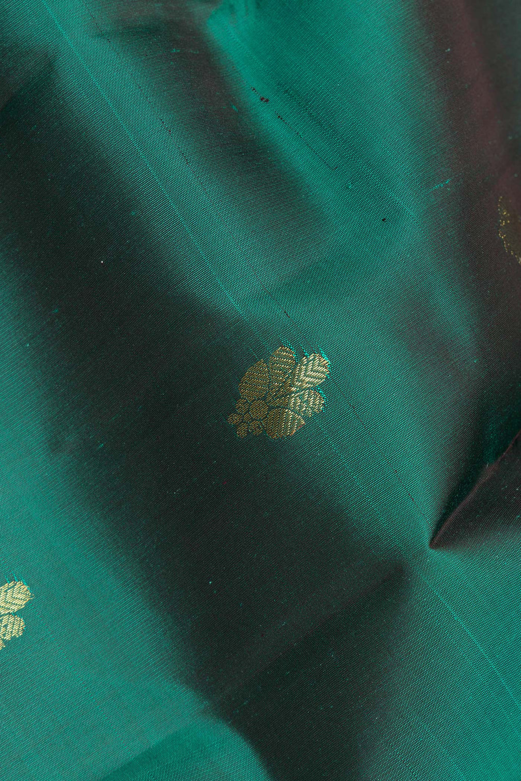 Close up of Pure Silk Bottle Green Kanjivaram Saree with Zari Butta on the body and Zari Border.  displaying folds