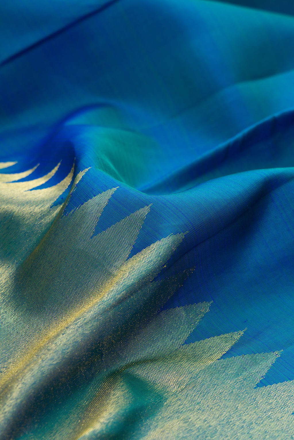 Close up of Pure Silk Peacock Blue Dual Tone Kanjivaram Saree with Plain Body and Rising Temple Border.  displaying folds