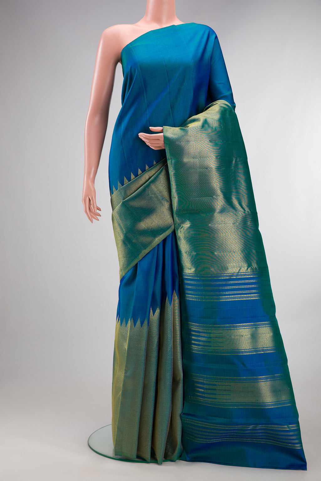 Pure Silk Peacock Blue Dual Tone Kanjivaram Saree with Plain Body and Rising Temple Border.  displayed on a mannequin