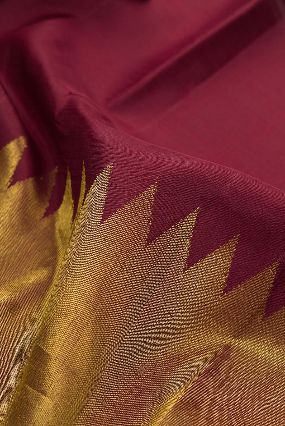 Close up of Pure Silk Maroon Kanjivaram Saree with Plain Body and Rising Temple Border.  displaying folds
