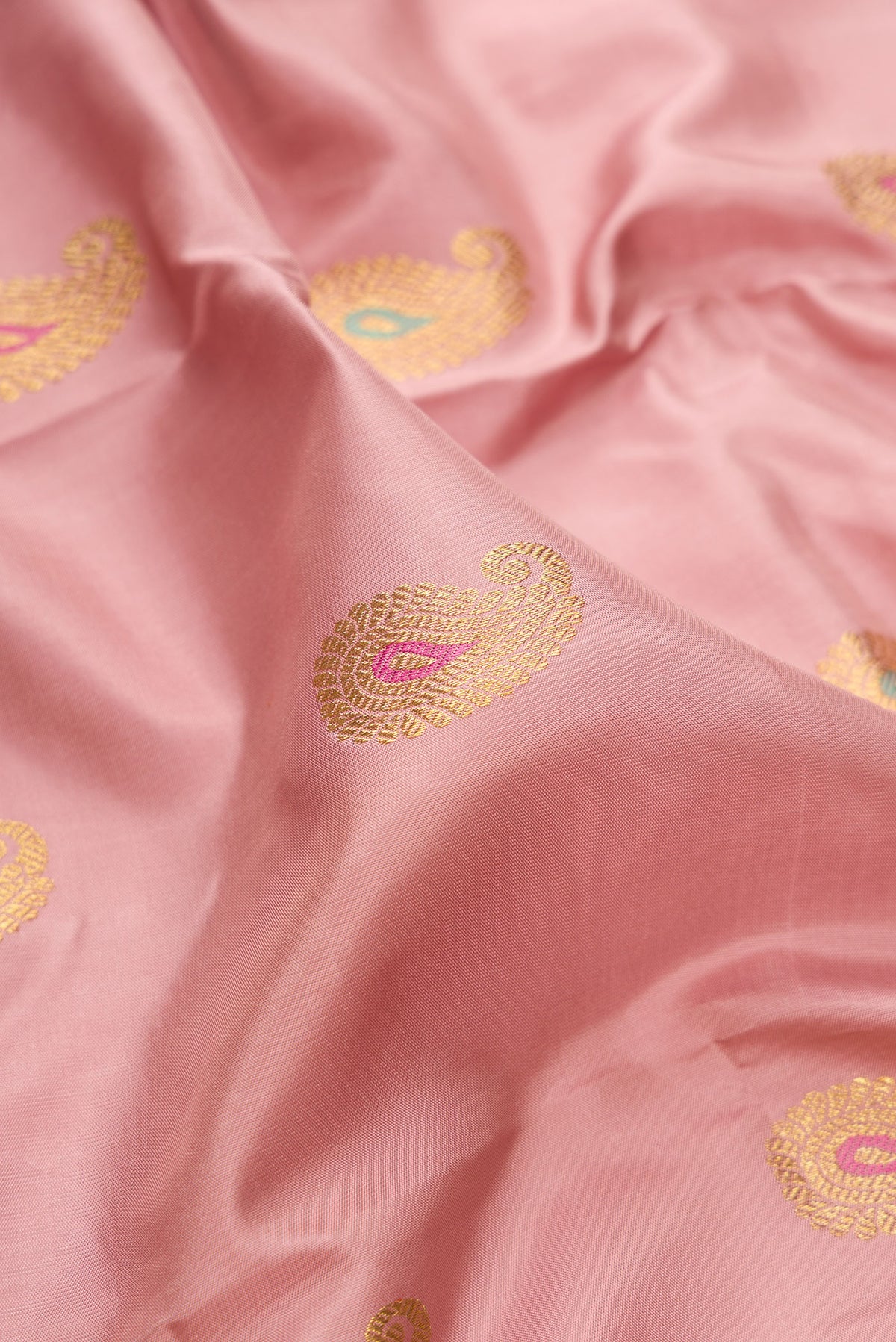 Close up of Pure Silk Pure Zari Peach Kanjivaram Saree with Zari And Thread Butta on the body and Fancy Border.  displaying folds