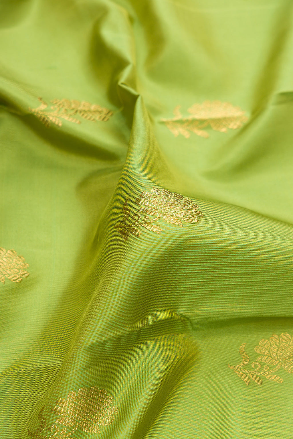 Close up of Pure Silk Pure Zari Parrot Green Kanjivaram Saree with Zari And Thread Butta on the body and Fancy Border.  displaying folds