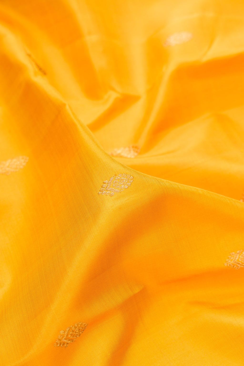 Close up of Pure Silk Pure Zari Yellow Kanjivaram Saree with Zari Butta on the body and Zari Border.  displaying folds