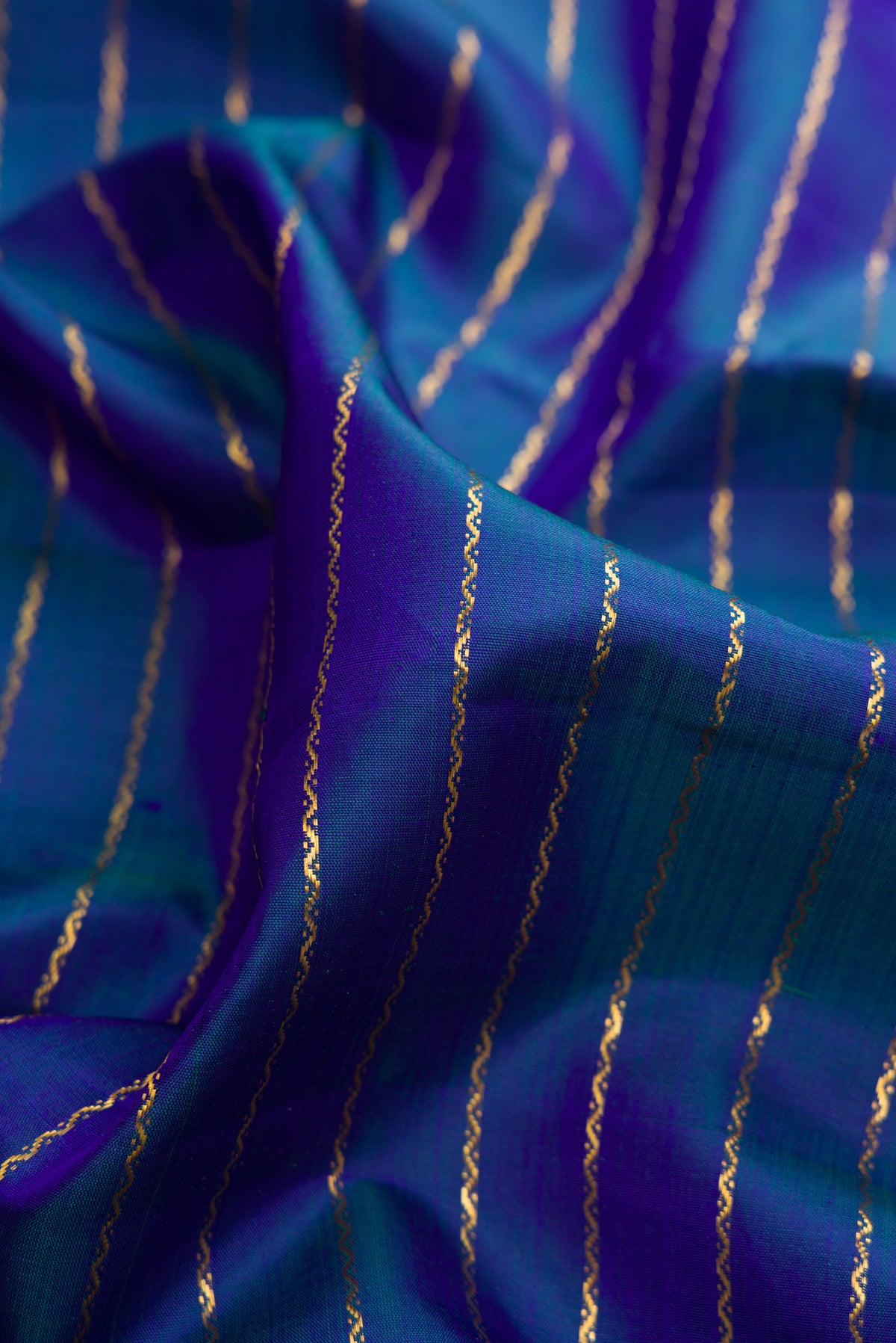 Close up of Pure Silk Peacock Blue Dual Tone Kanjivaram Nine Yards Saree with Veldhari on the body and Zari Border.  displaying folds
