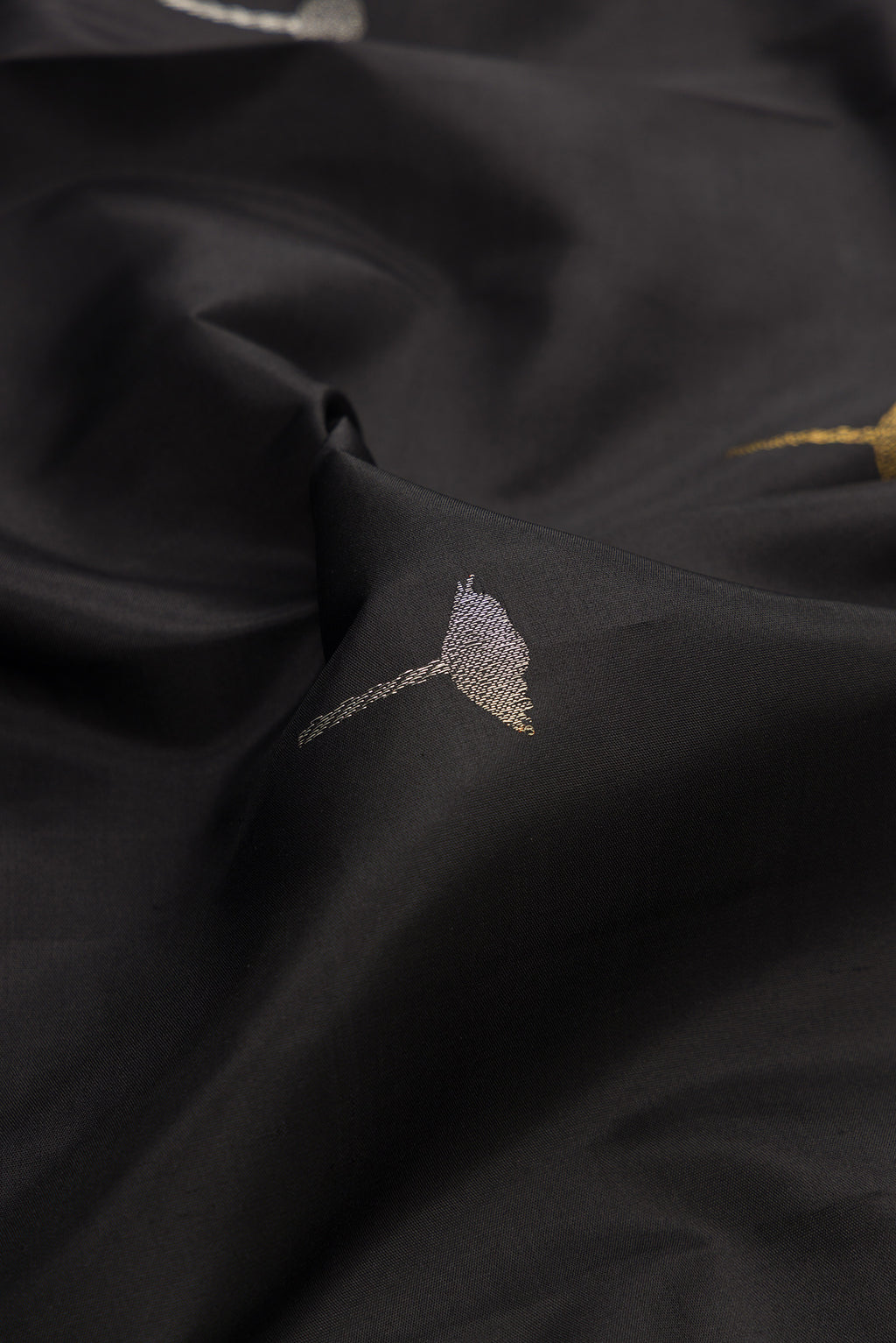 Close up of Pure Silk Black Kanchipuram Saree with Zari Butta on the body and Without Border.  displaying folds