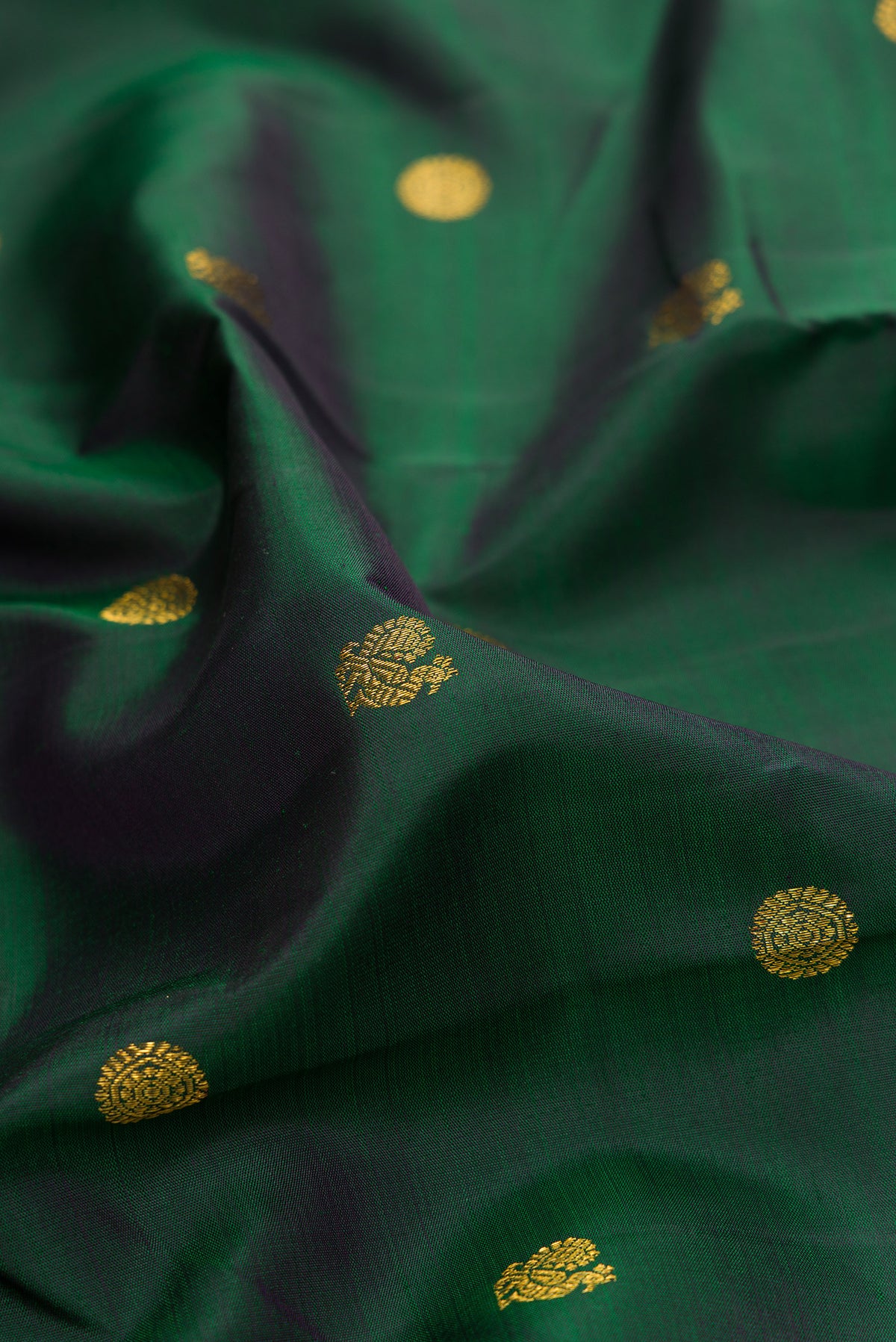 Close up of Pure Silk Bottle Green Kanjivaram Saree with Zari Butta on the body and Zari Border.  displaying folds