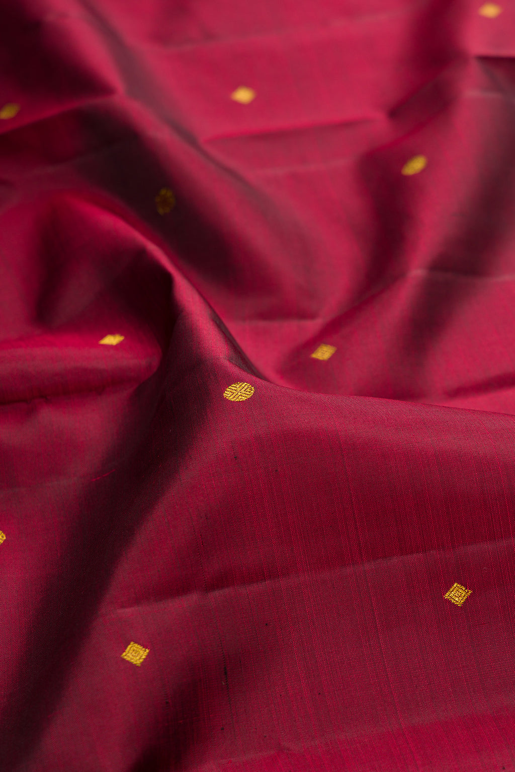 Close up of Pure Silk Maroon Kanjivaram Saree with Zari Butta on the body and Zari Border.  displaying folds