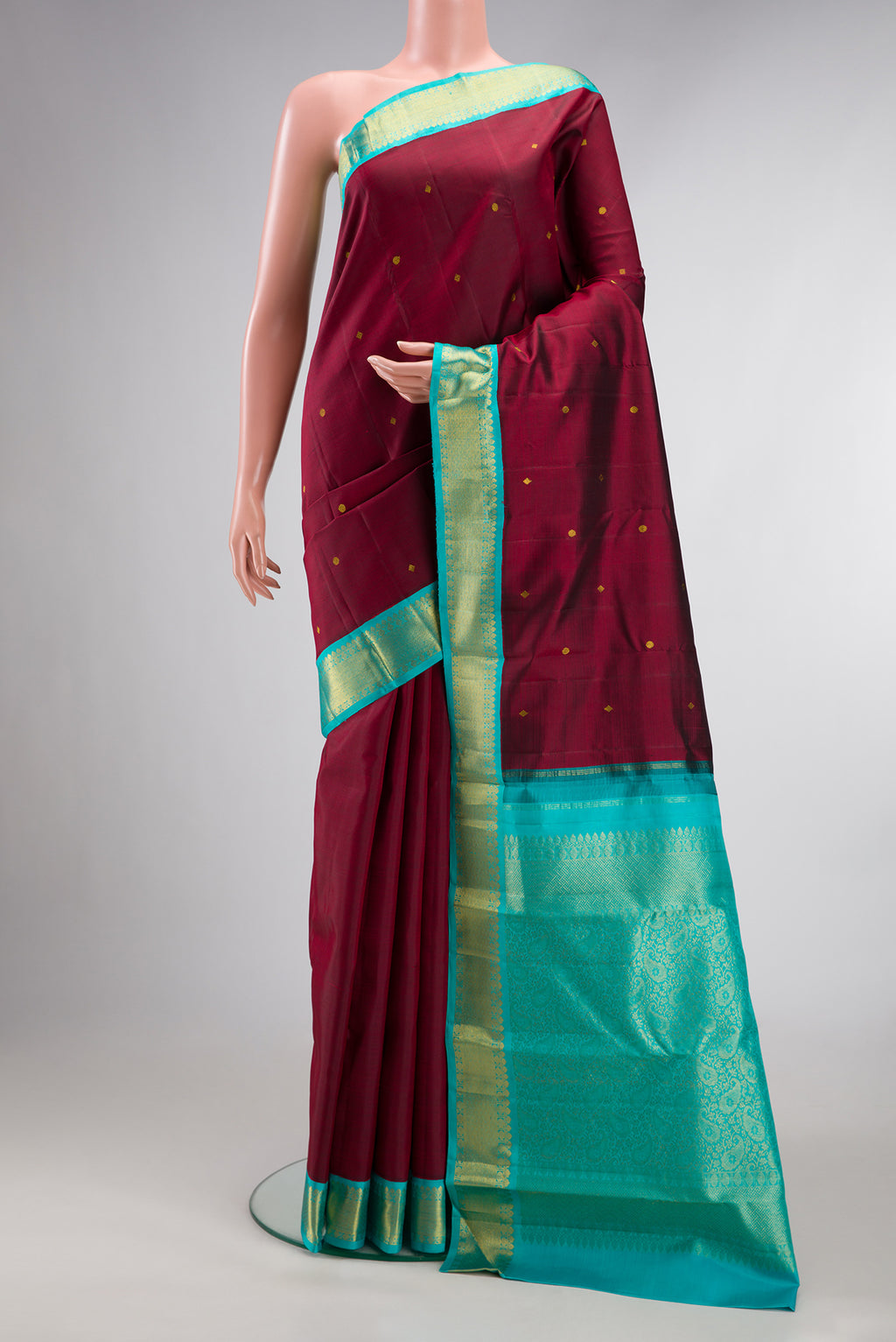 Pure Silk Maroon Kanjivaram Saree with Zari Butta on the body and Zari Border.  displayed on a mannequin