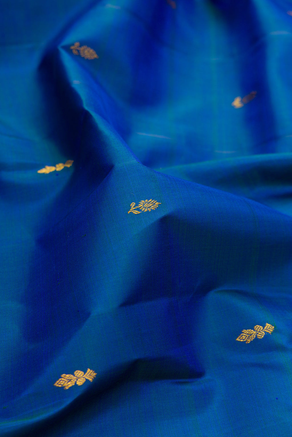 Close up of Pure Silk Peacock Blue Dual Tone Kanjivaram Saree with Zari Butta on the body and Zari Border.  displaying folds