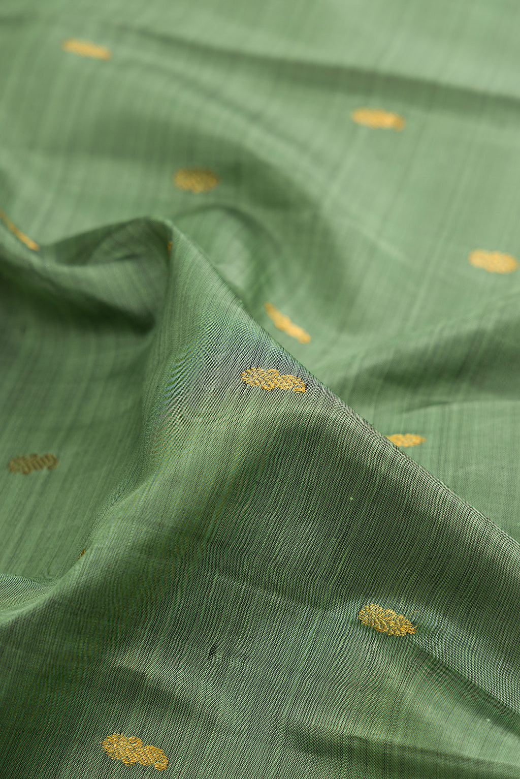 Close up of Pure Silk Sage Green Kanchipuram Saree with Zari Butta on the body and Zari Border.  displaying folds