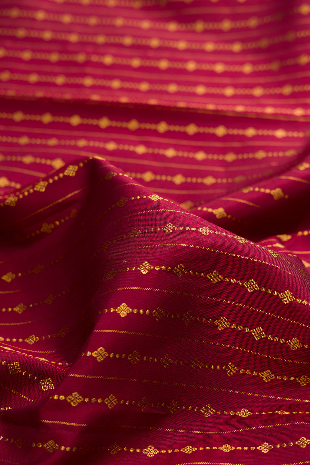 Close up of Pure Silk Maroon Kanjivaram Saree with Zari Butta on the body and Fancy Border.  displaying folds