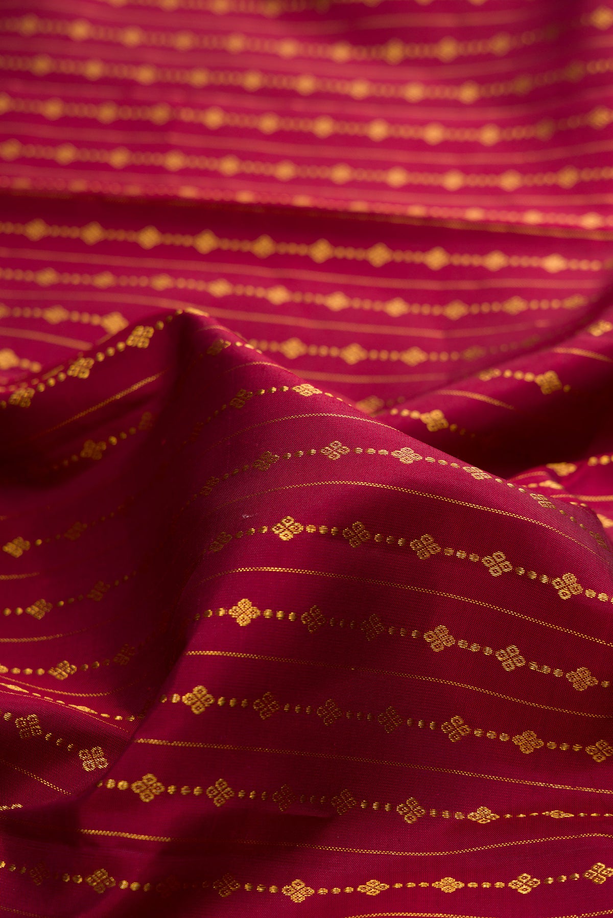 Close up of Pure Silk Maroon Kanjivaram Saree with Zari Butta on the body and Fancy Border.  displaying folds