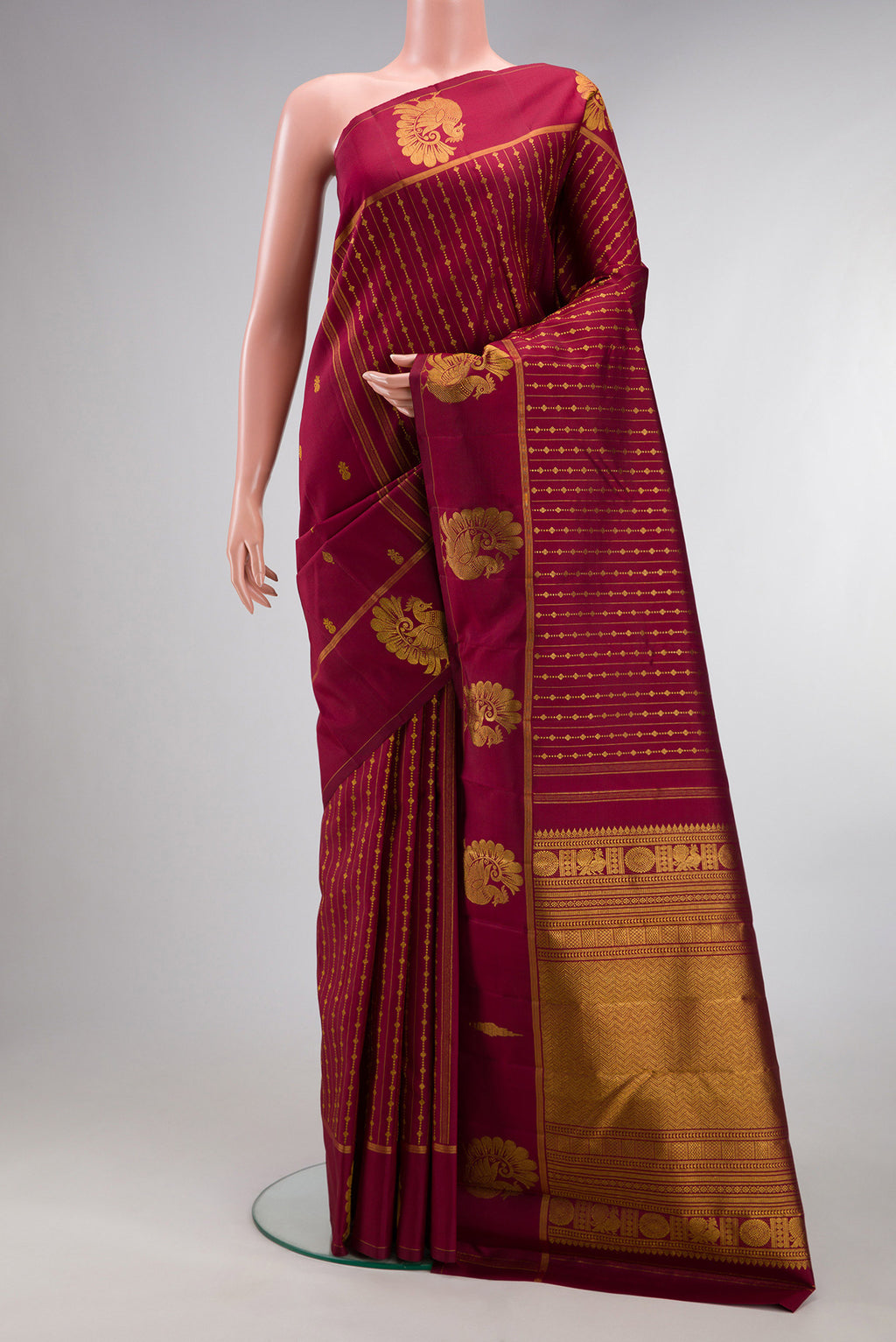 Pure Silk Maroon Kanjivaram Saree with Zari Butta on the body and Fancy Border.  displayed on a mannequin