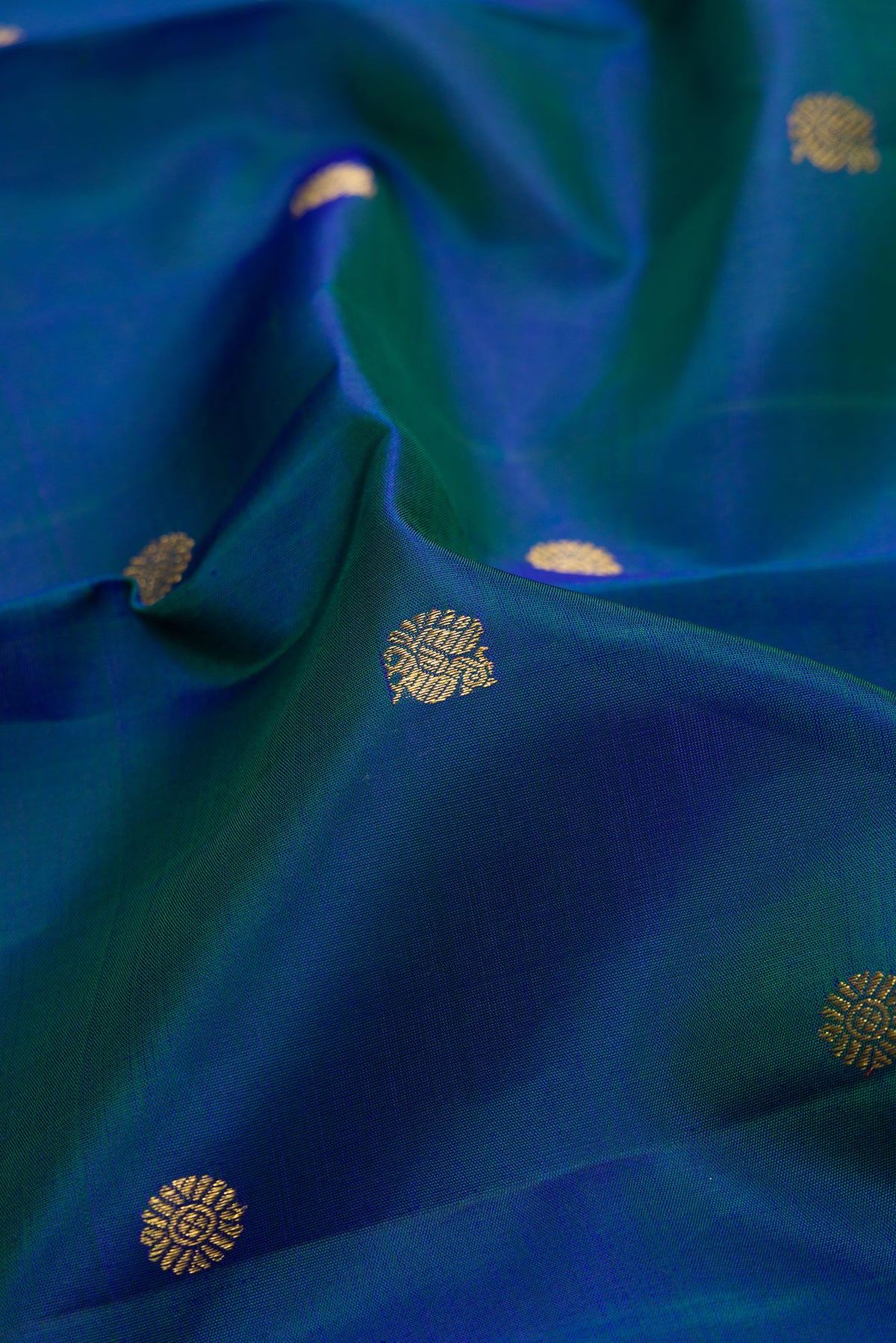 Close up of Pure Silk Peacock Blue Dual Tone Kanchipuram Saree with Zari Butta on the body and Zari Border.  displaying folds