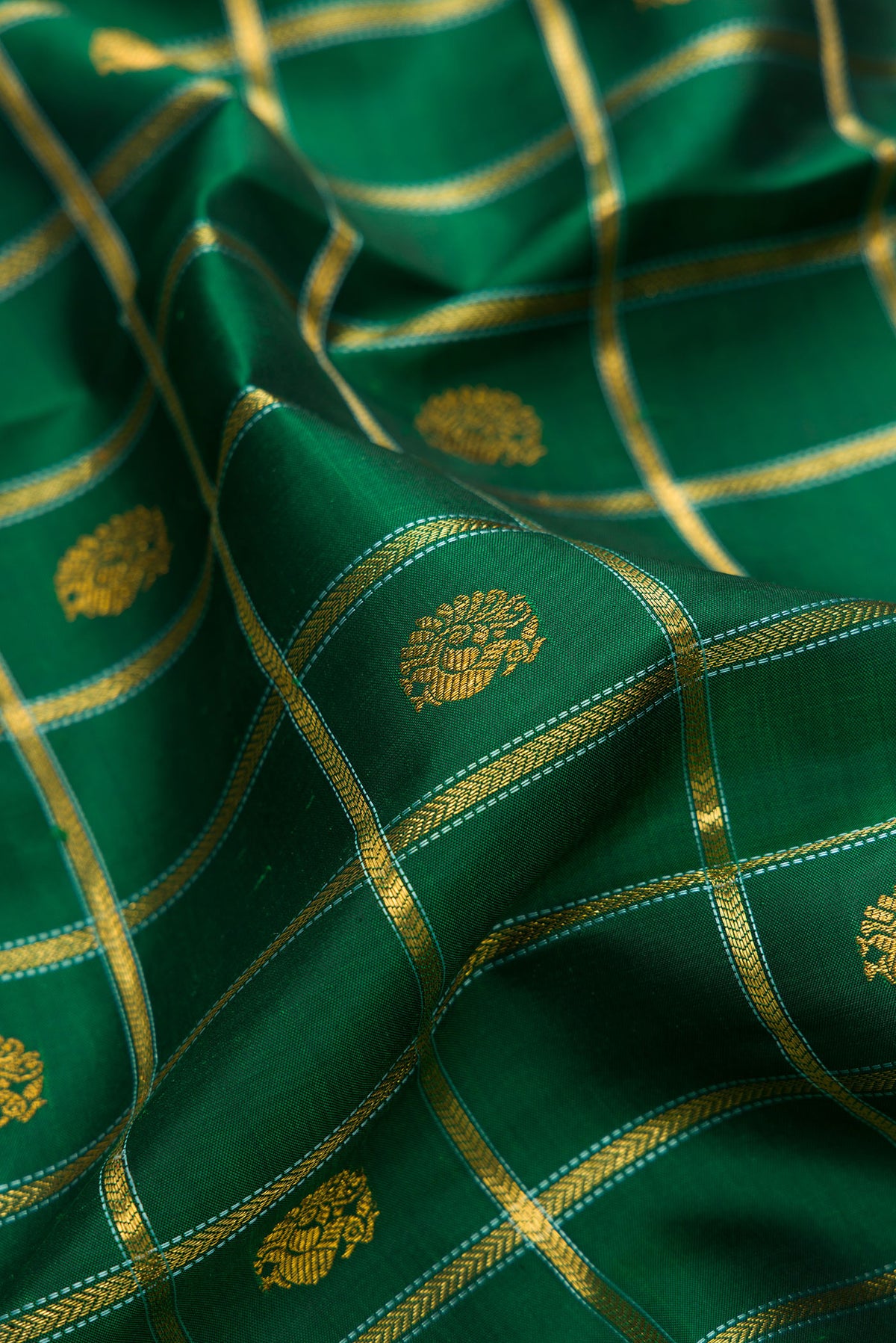 Close up of Pure Silk Bottle Green Kanchipuram Saree with Checked design on the body and Zari And Thread Border.  displaying folds