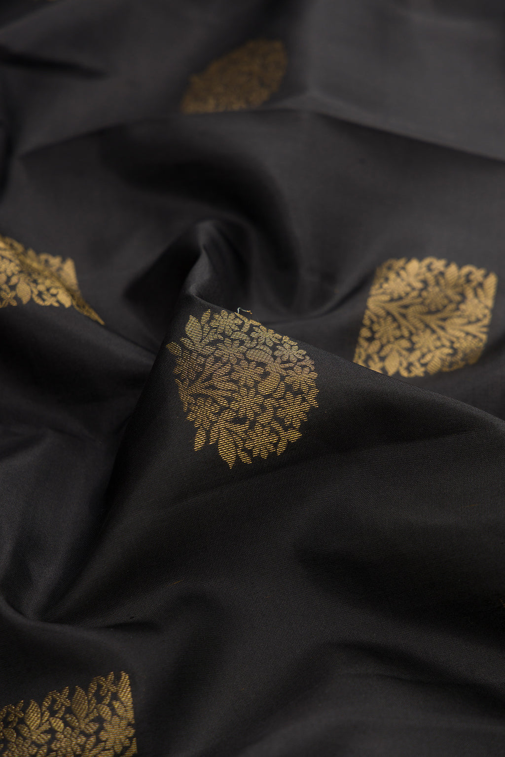 Close up of Pure Silk Black Kanchipuram Saree with Zari Butta on the body and Zari Border.  displaying folds