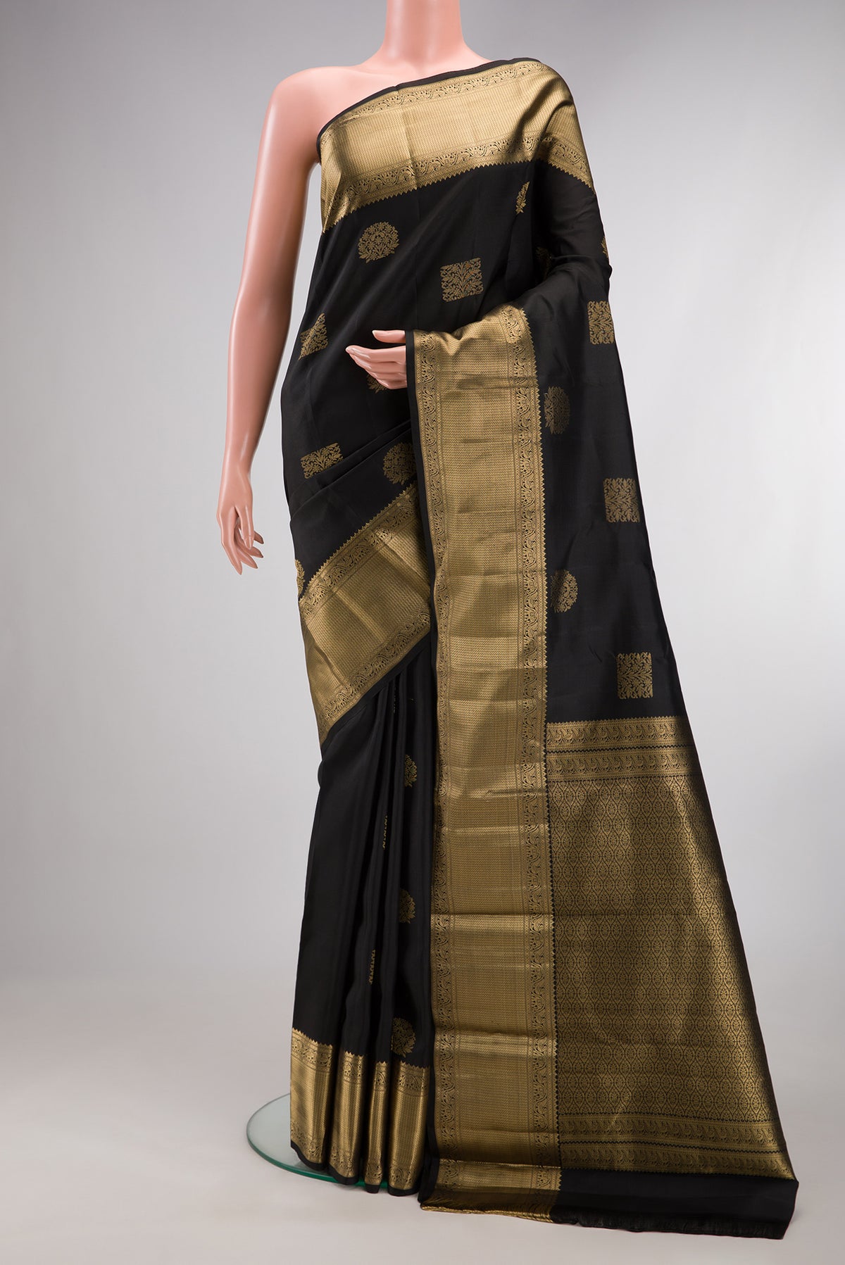Pure Silk Black Kanchipuram Saree with Zari Butta on the body and Zari Border.  displayed on a mannequin