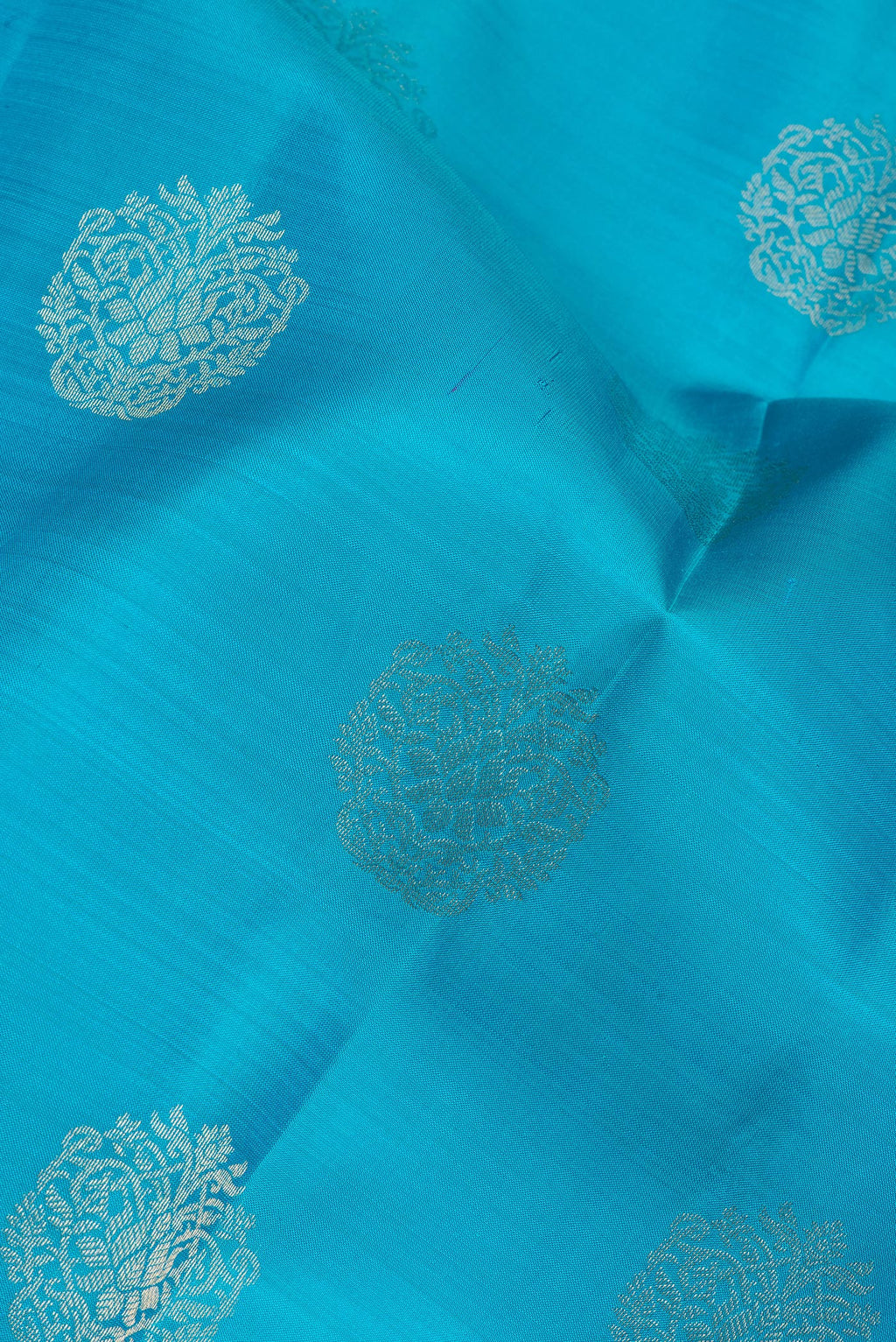 Close up of Pure Silk Sky Blue Kanchipuram Saree with Zari Butta on the body and Zari Border.  displaying folds