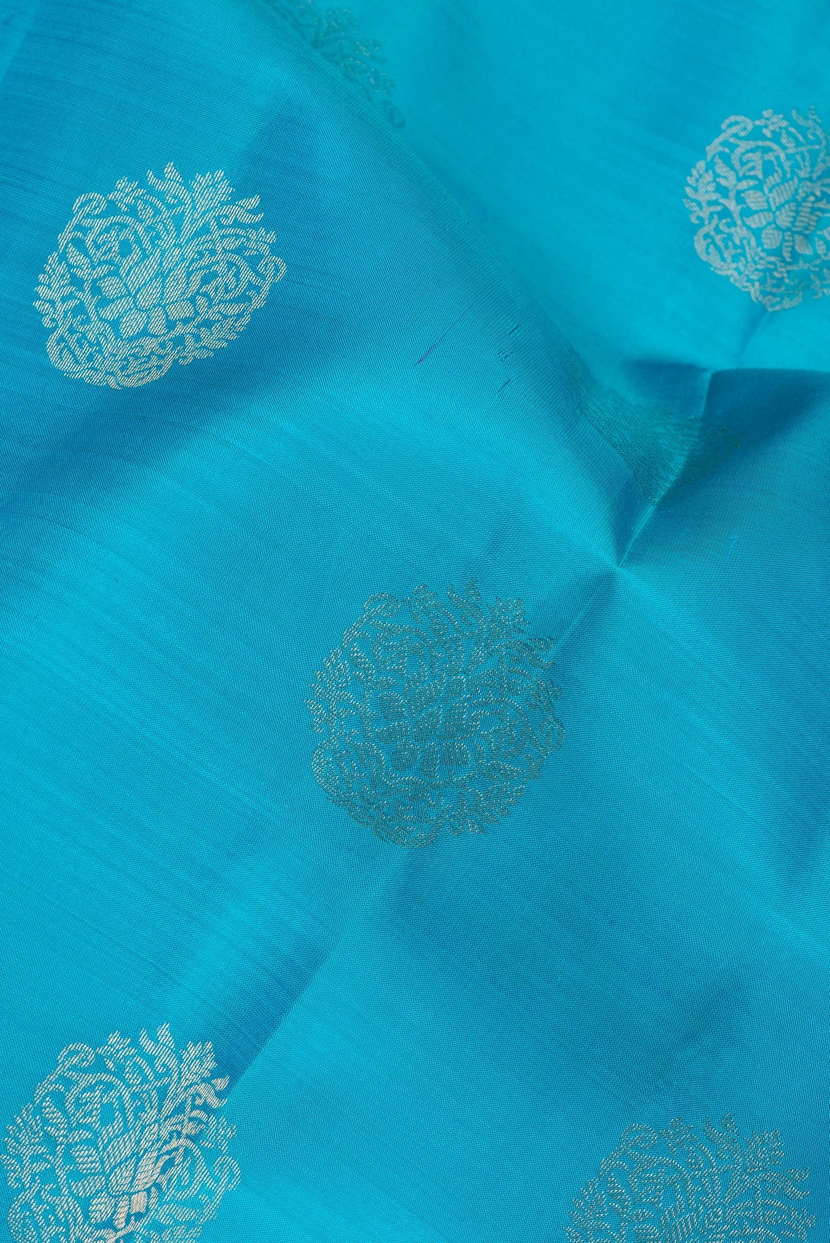 Close up of Pure Silk Sky Blue Kanchipuram Saree with Zari Butta on the body and Zari Border.  displaying folds