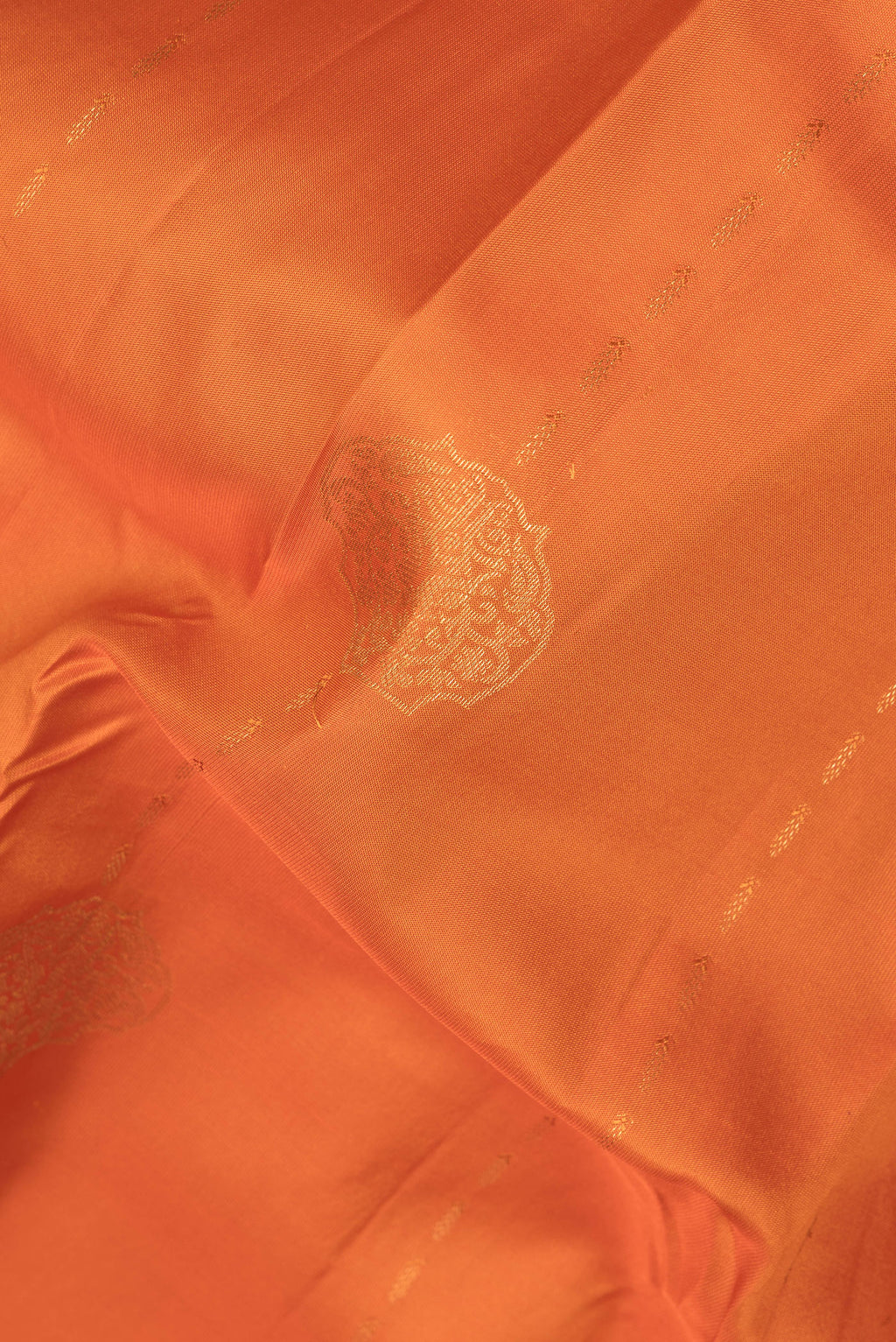 Close up of Pure Silk Orange Kanchipuram Saree with Zari Butta on the body and Zari Border.  displaying folds
