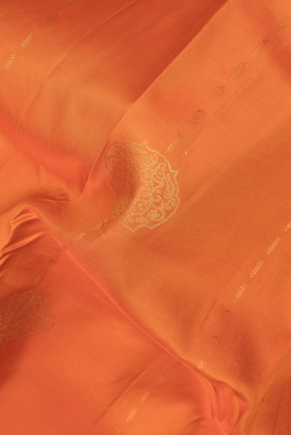 Close up of Pure Silk Orange Kanchipuram Saree with Zari Butta on the body and Zari Border.  displaying folds