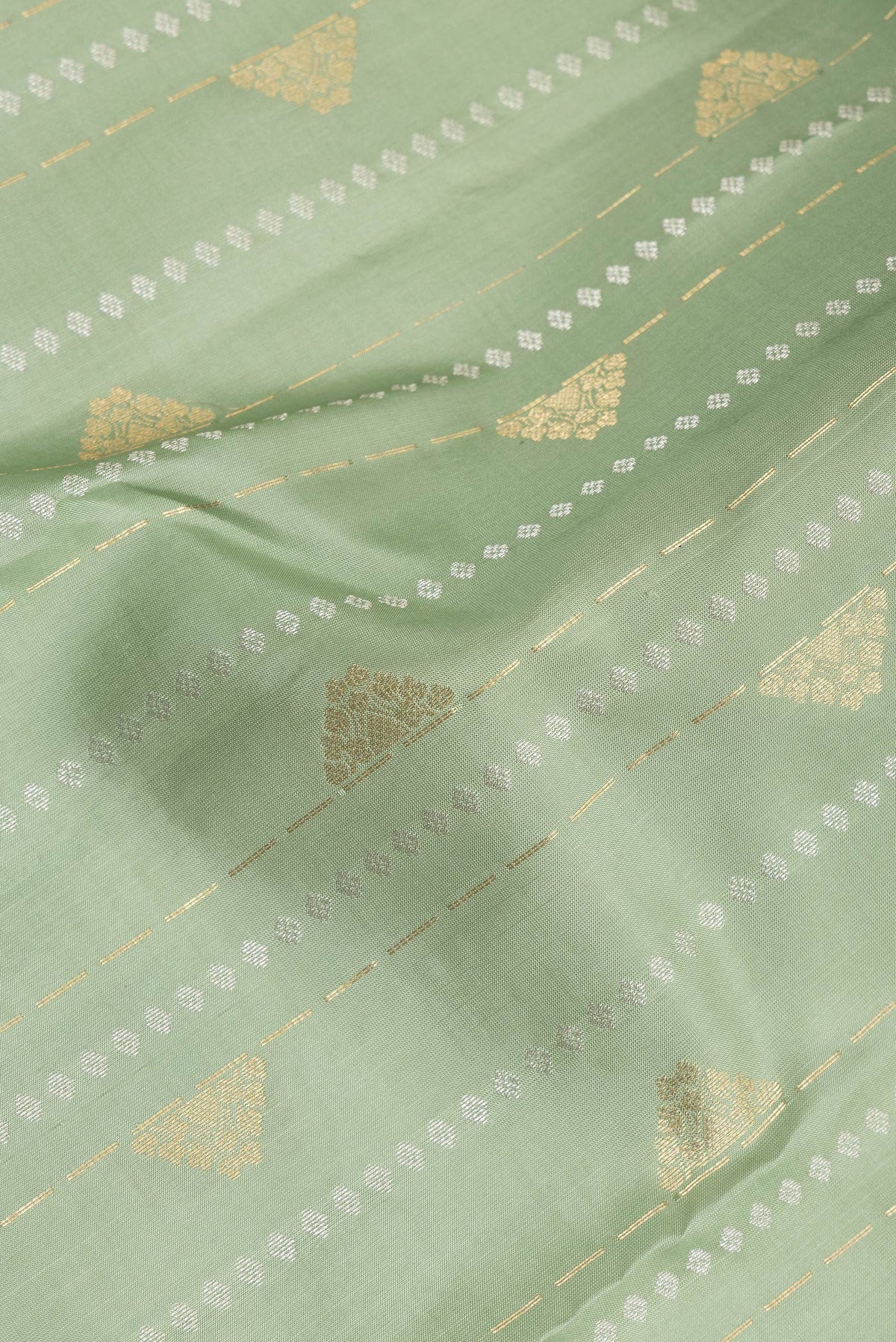 Close up of Pure Silk Pista Green Kanchipuram Saree with Zari Butta on the body and Zari Border.  displaying folds
