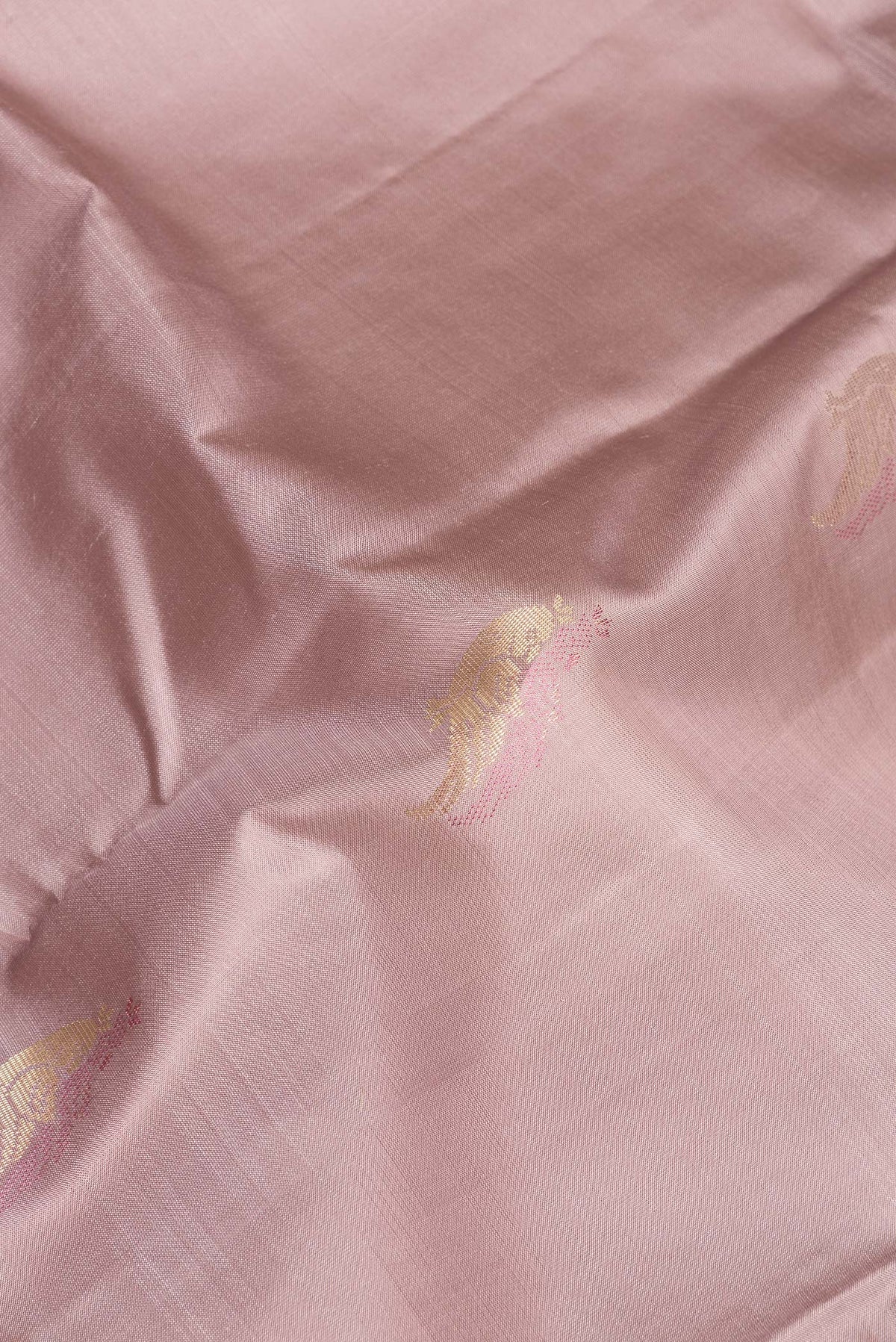 Close up of Pure Silk Rose Gold Kanchipuram Saree with Zari Butta on the body and Without Border.  displaying folds
