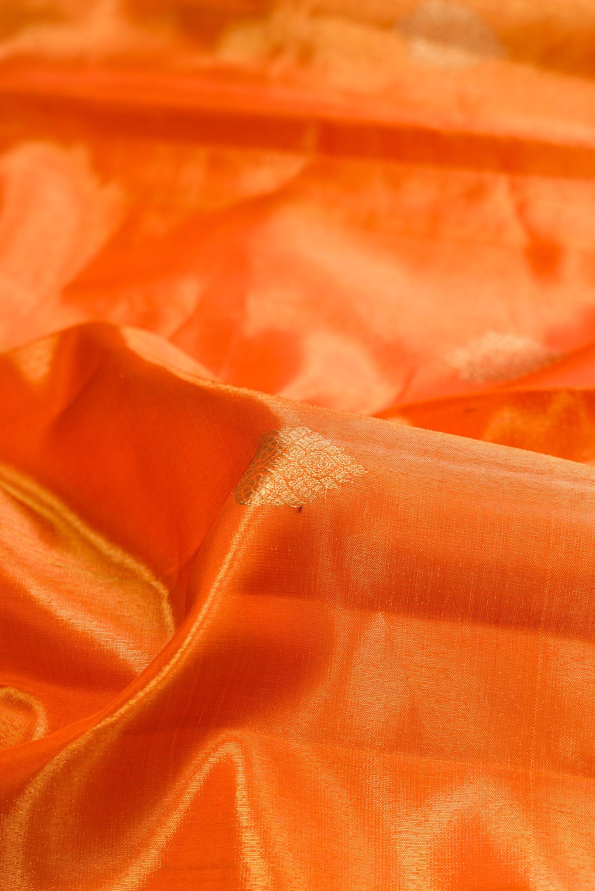 Close up of Orange Dual Tone Kanjivaram Tissue Saree with Zari Butta on the body and Fancy Border.  displaying folds