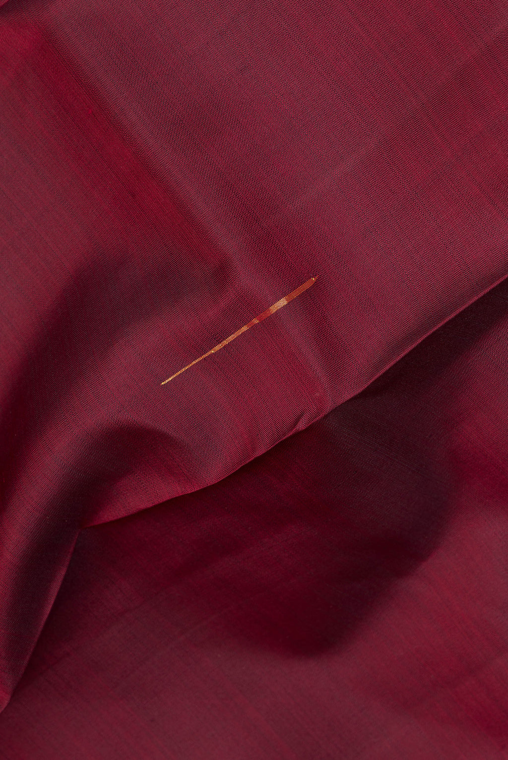 Close up of Pure Silk Maroon Kanjivaram Saree with Zari Butta on the body and Zari Border.  displaying folds