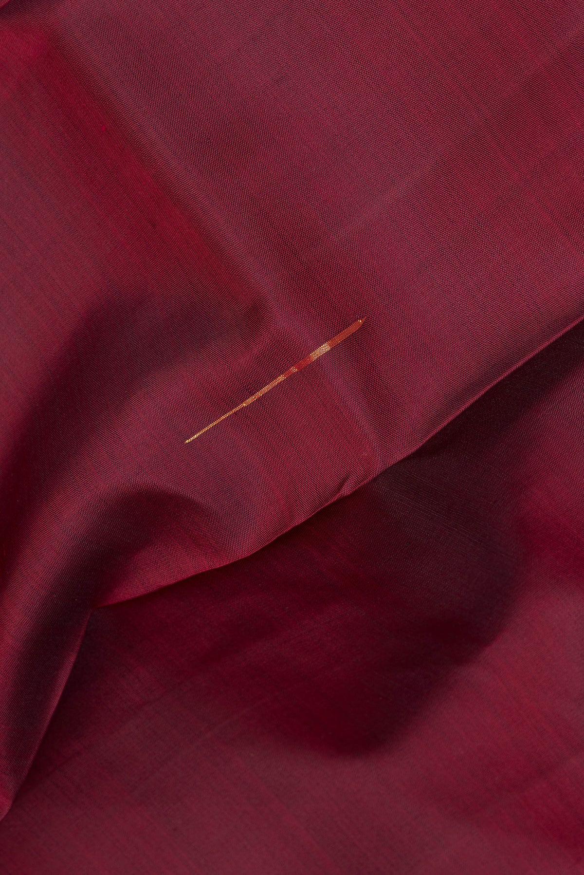 Close up of Pure Silk Maroon Kanjivaram Saree with Zari Butta on the body and Zari Border.  displaying folds