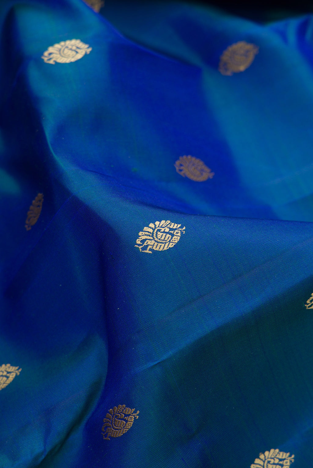 Close up of Pure Silk Peacock Blue Dual Tone Kanjivaram Saree with Thread Butta on the body and Thread Border.  displaying folds