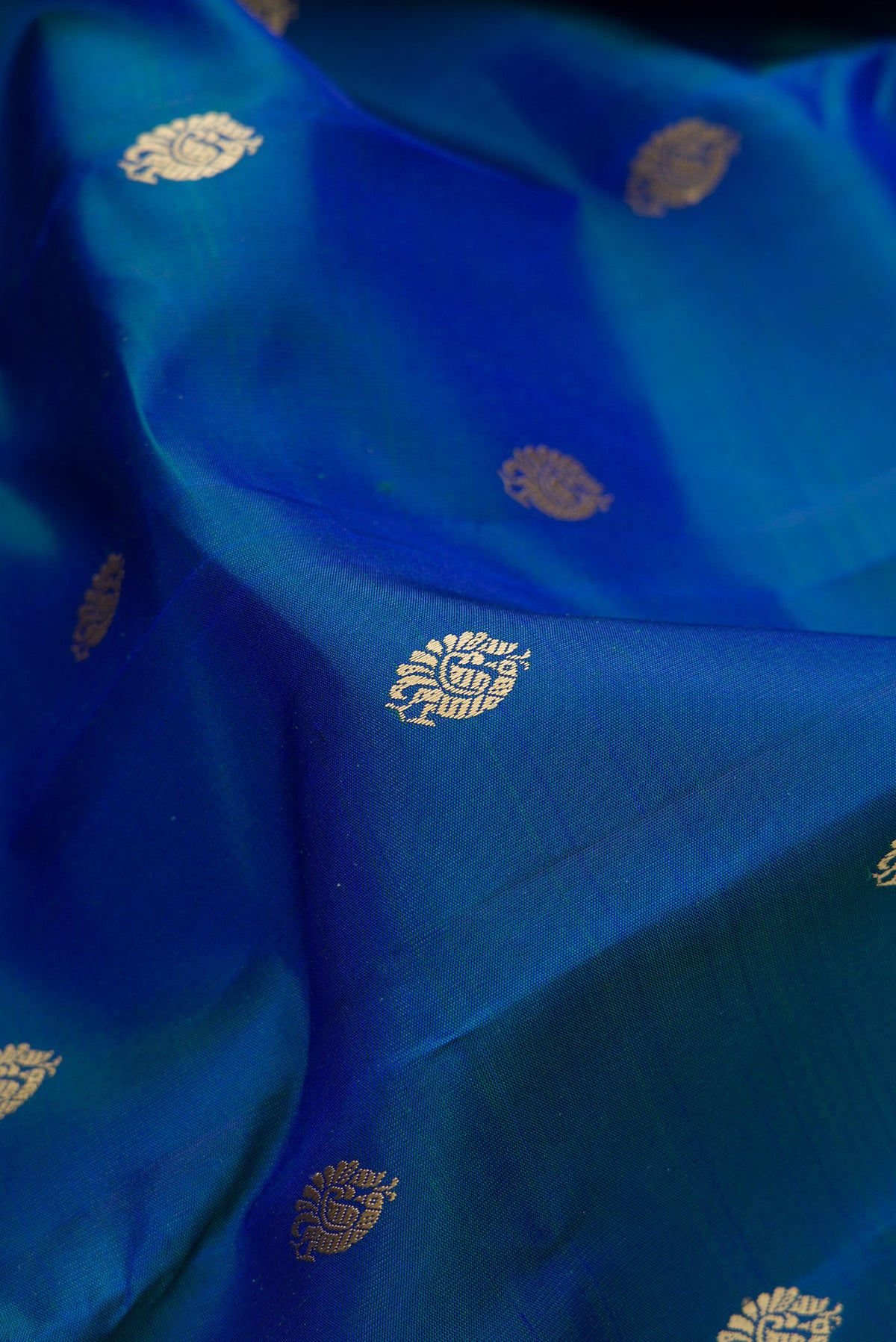 Close up of Pure Silk Peacock Blue Dual Tone Kanjivaram Saree with Thread Butta on the body and Thread Border.  displaying folds